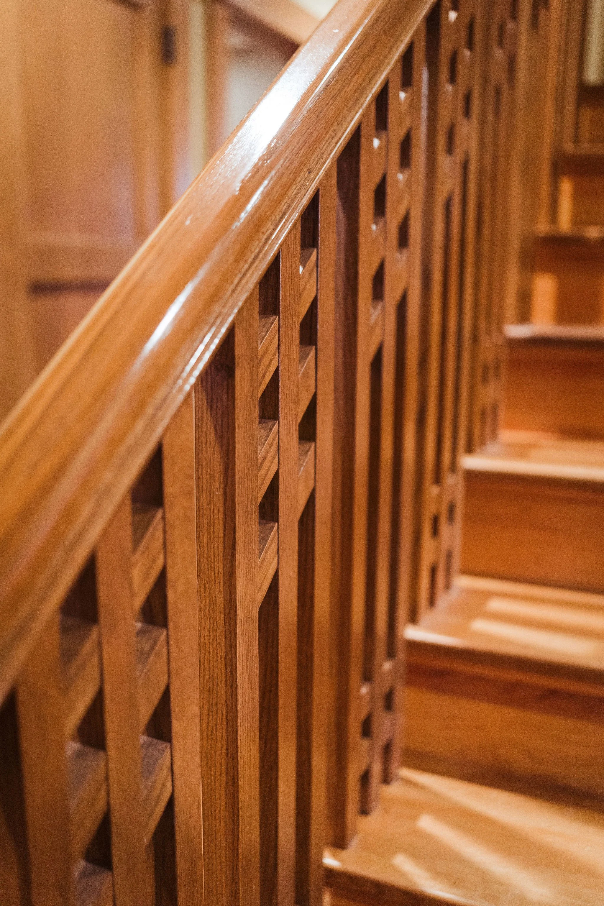 Close-up of a wooden staircase railing and steps with a glossy finish.