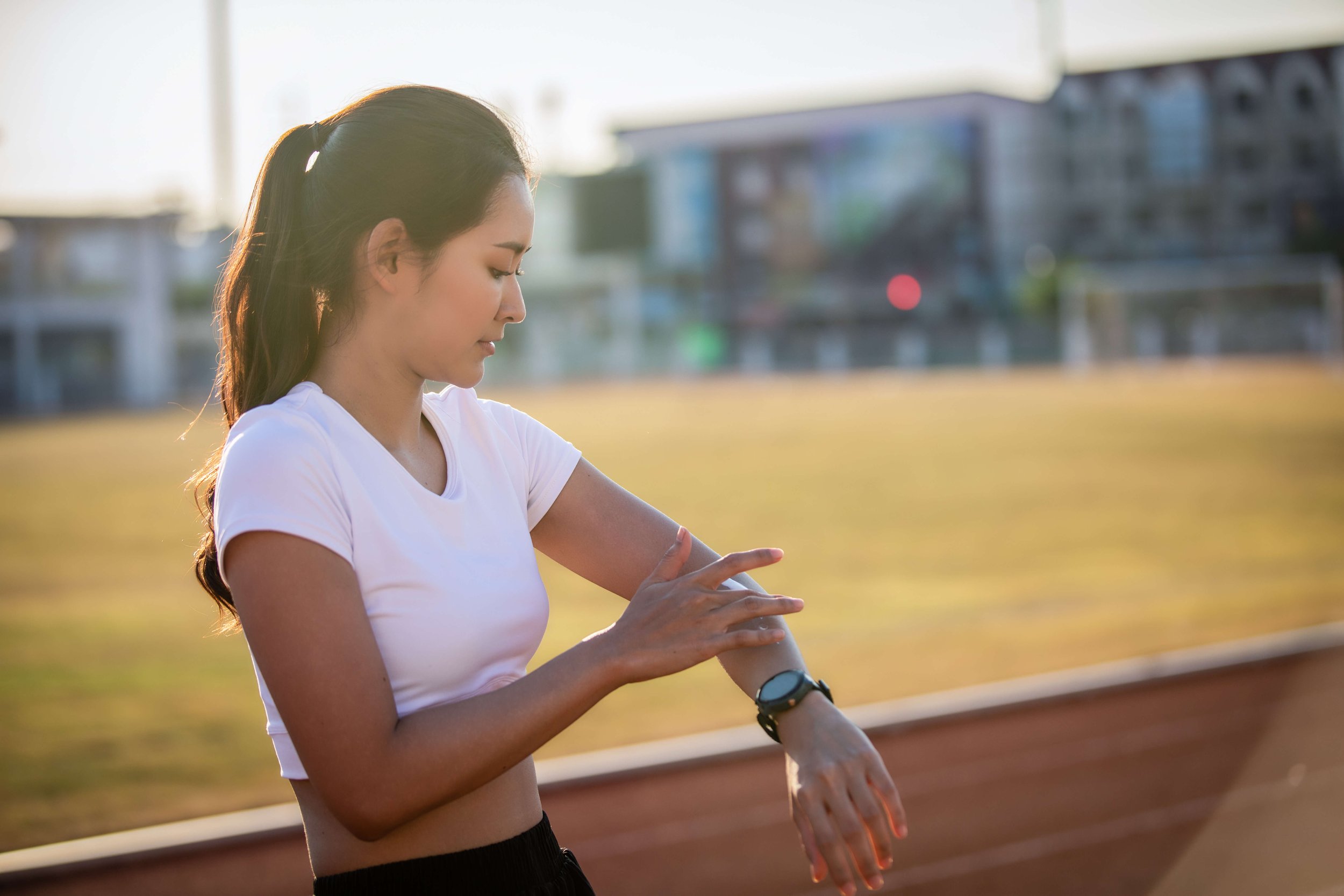 Woman in athletic wear checking smartwatch on a track