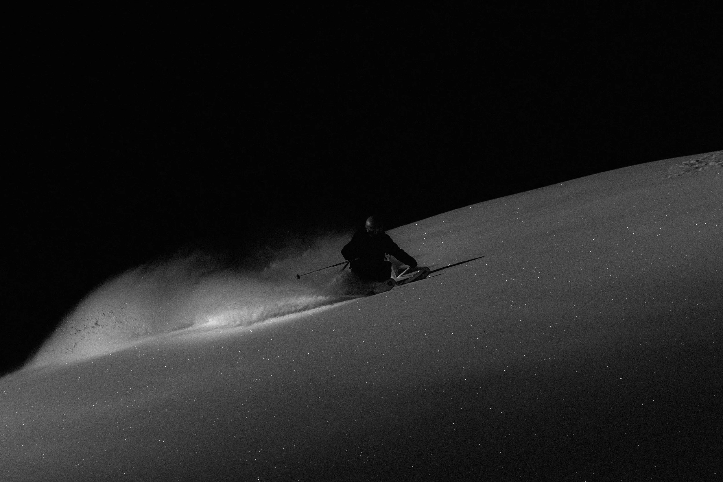 Esquiador descendiendo una pendiente nevada bajo un cielo oscuro.