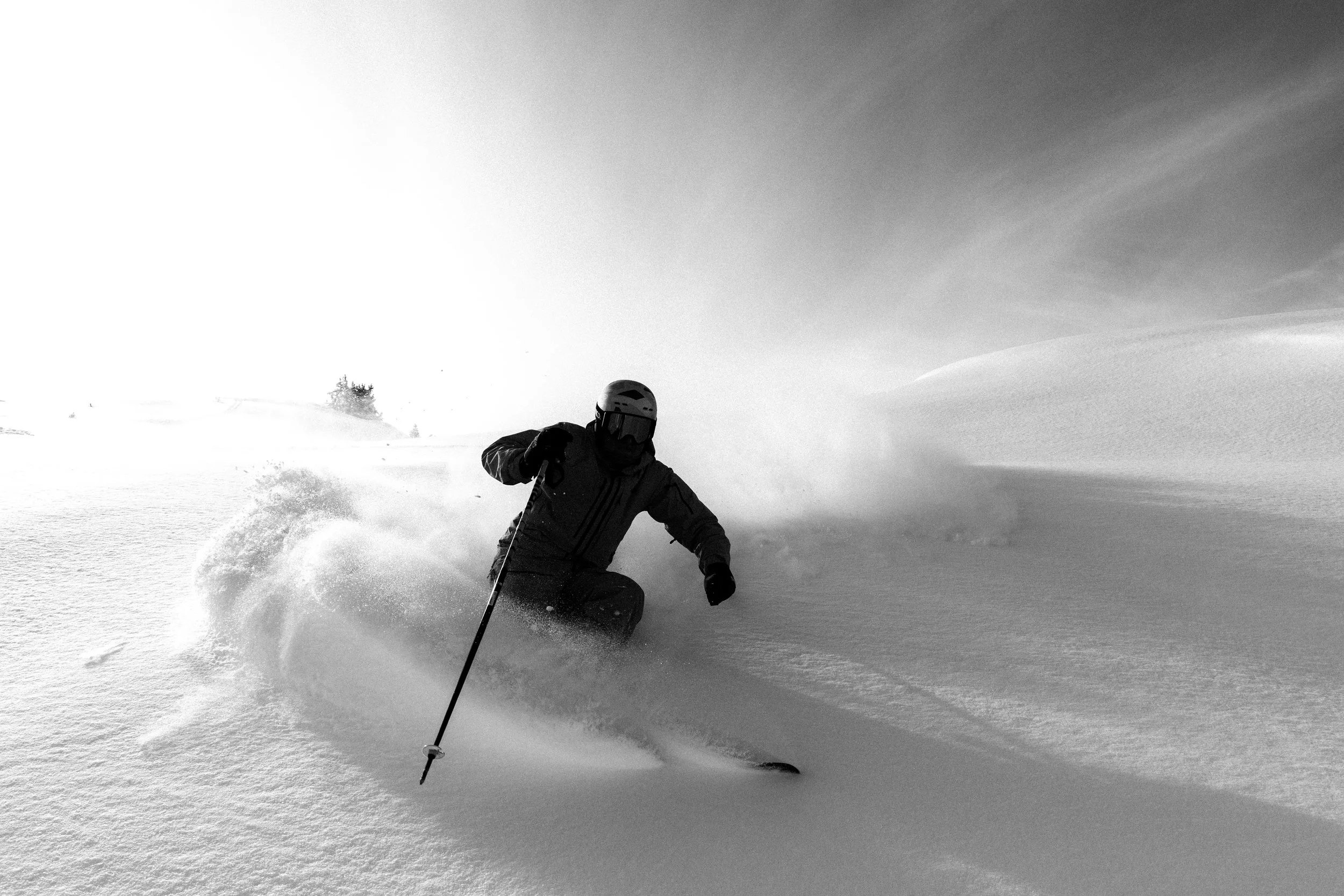 Esquiador con casco y gafas en la nieve, haciendo una curva mientras desciende por una pendiente cubierta de nieve.