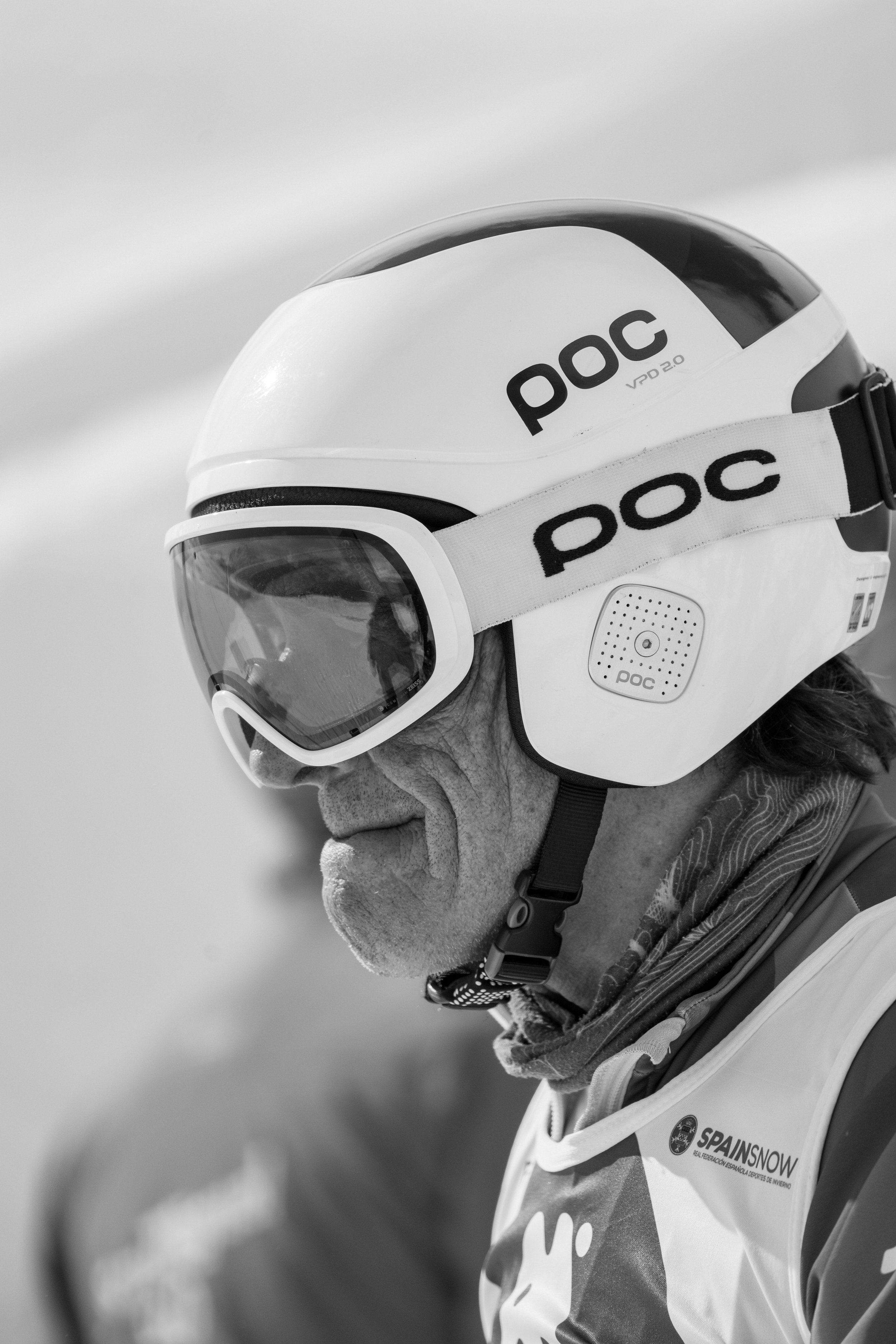 Casco de esquí blanco con gafas y gafas protectoras, con logotipo 'poc' y etiqueta 'SPAINSNOW', en un entorno de invierno.