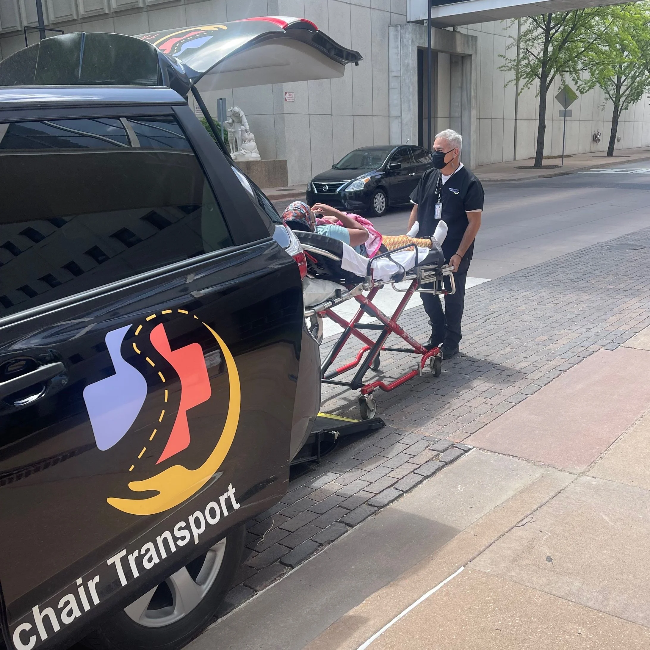 Entrusted Transport driver assisting senior on stretcher into medical transport van in Tulsa