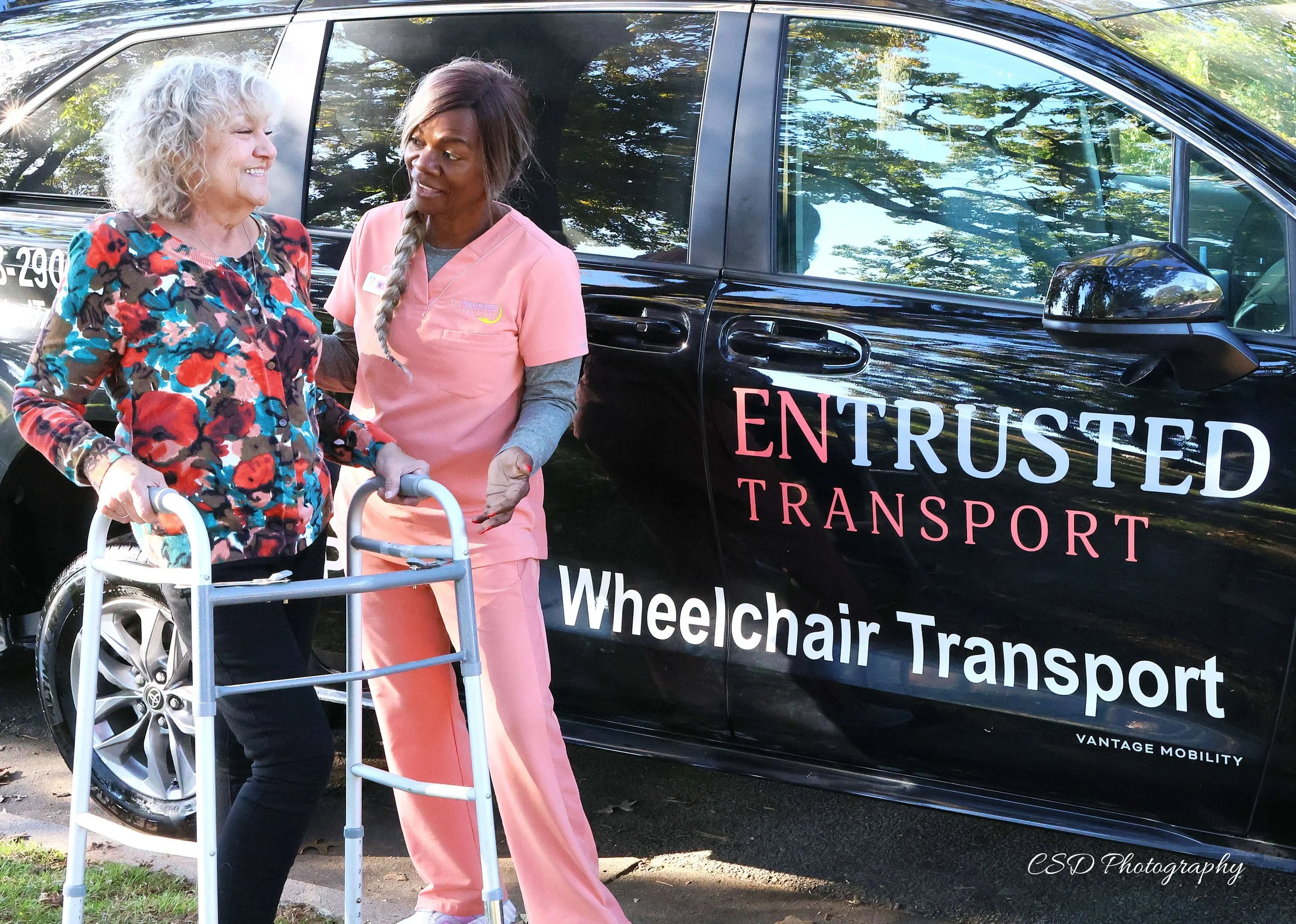 Entrusted Transport staff member assisting an ambulatory rider using a walker during medical transportation service in Northwest Arkansas.