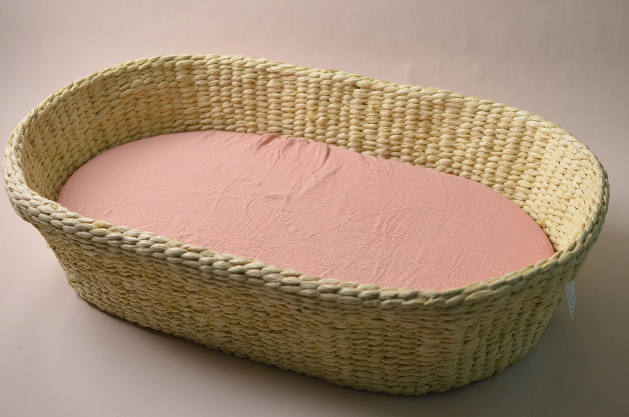 A wicker bassinet with a white inner lining and a blue fabric cover