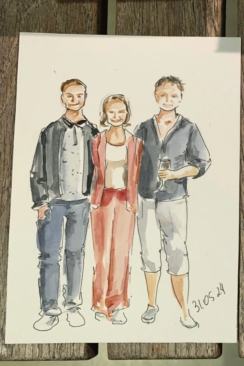 Watercolor illustration of three people standing together; two men on either side of a woman, one holding a glass of wine, with the date 31.05.24 written on the bottom right.