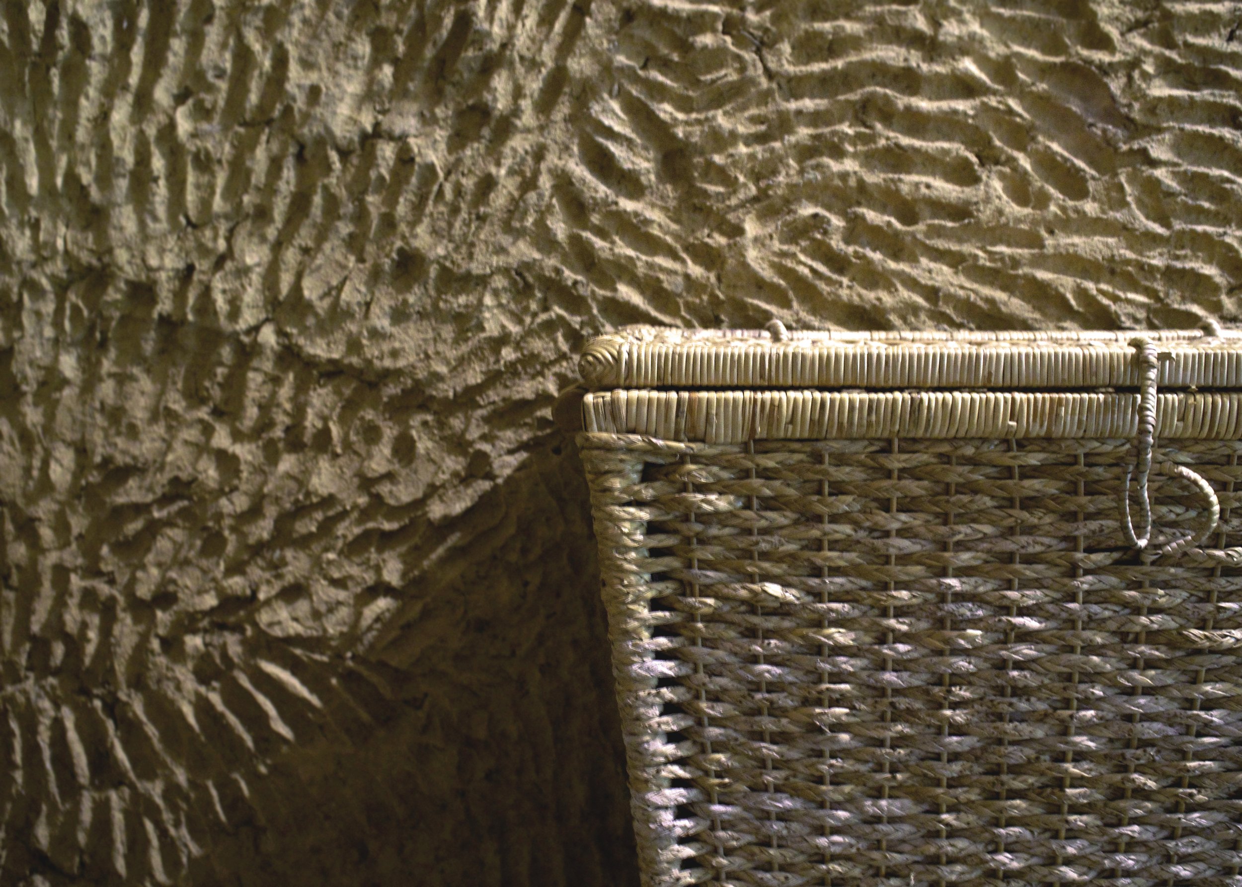 Close-up of a woven basket against a textured, ridged traditionnal wall.