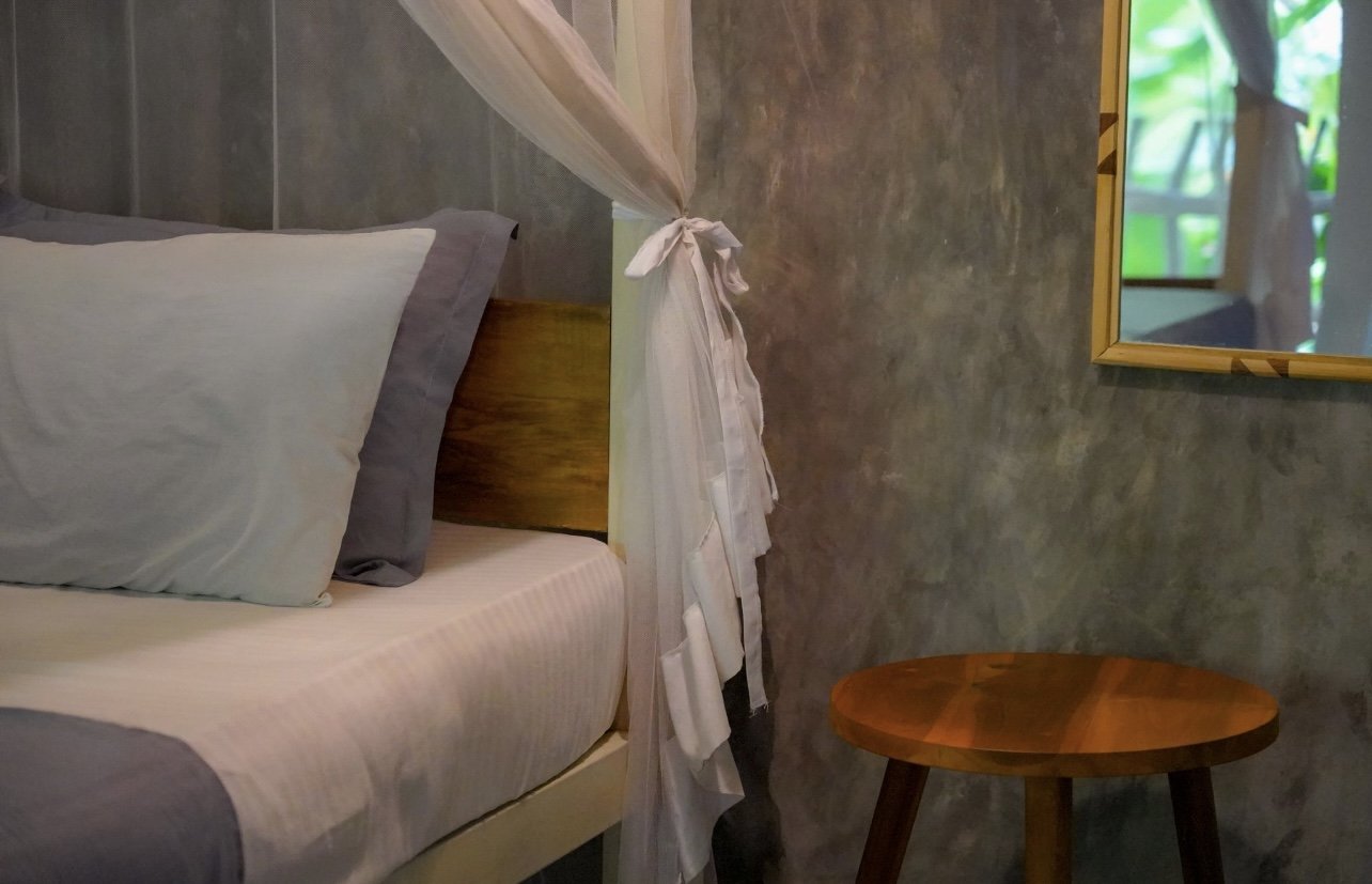 Cozy bedroom interior of the Ceylon suite, featuring wood and concrete design.