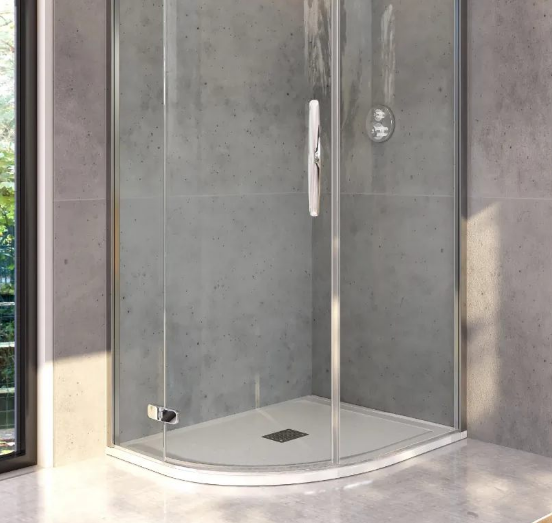 Glass shower enclosure with a curved corner, silver door handle, gray concrete walls, and a floor drain.