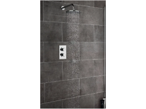 Showerhead with water spraying over dark gray tiled shower wall.