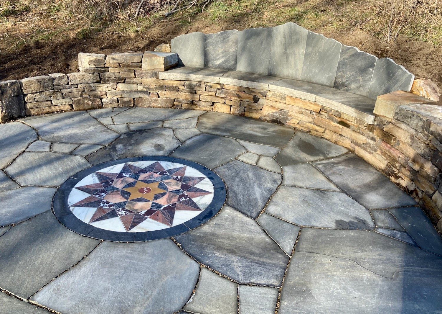 A long stone couch overlooking a mosaic patio, Marshall