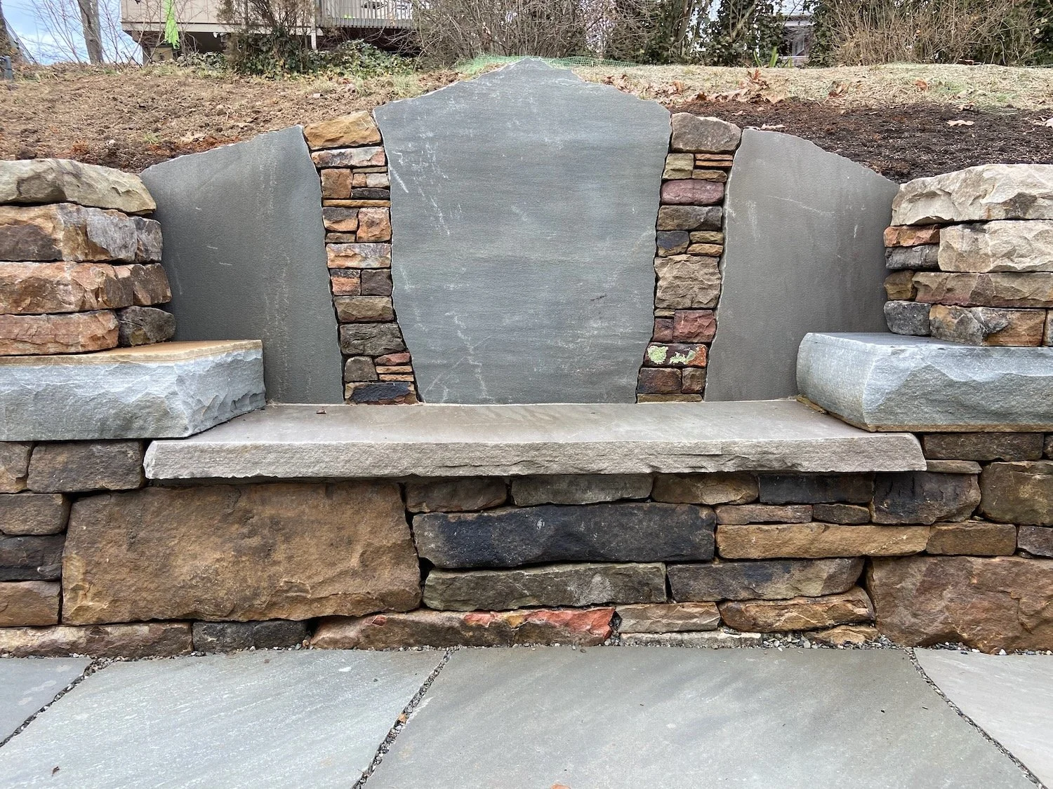 Stone couch in a fieldstone wall, with stacked wall details embedded in the seatback, Asheville