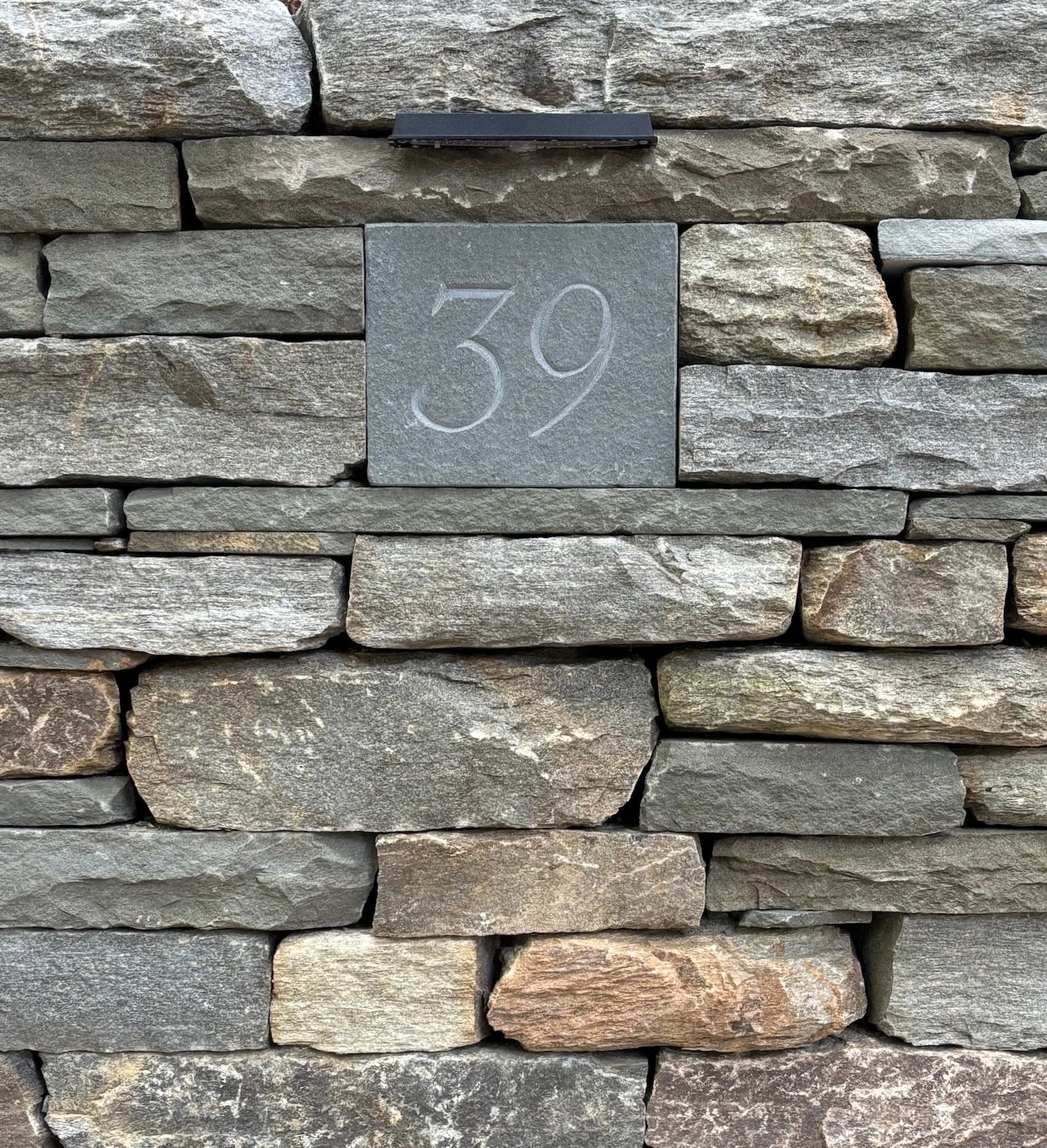 House number carved in bluestone, embedded in drystone wall