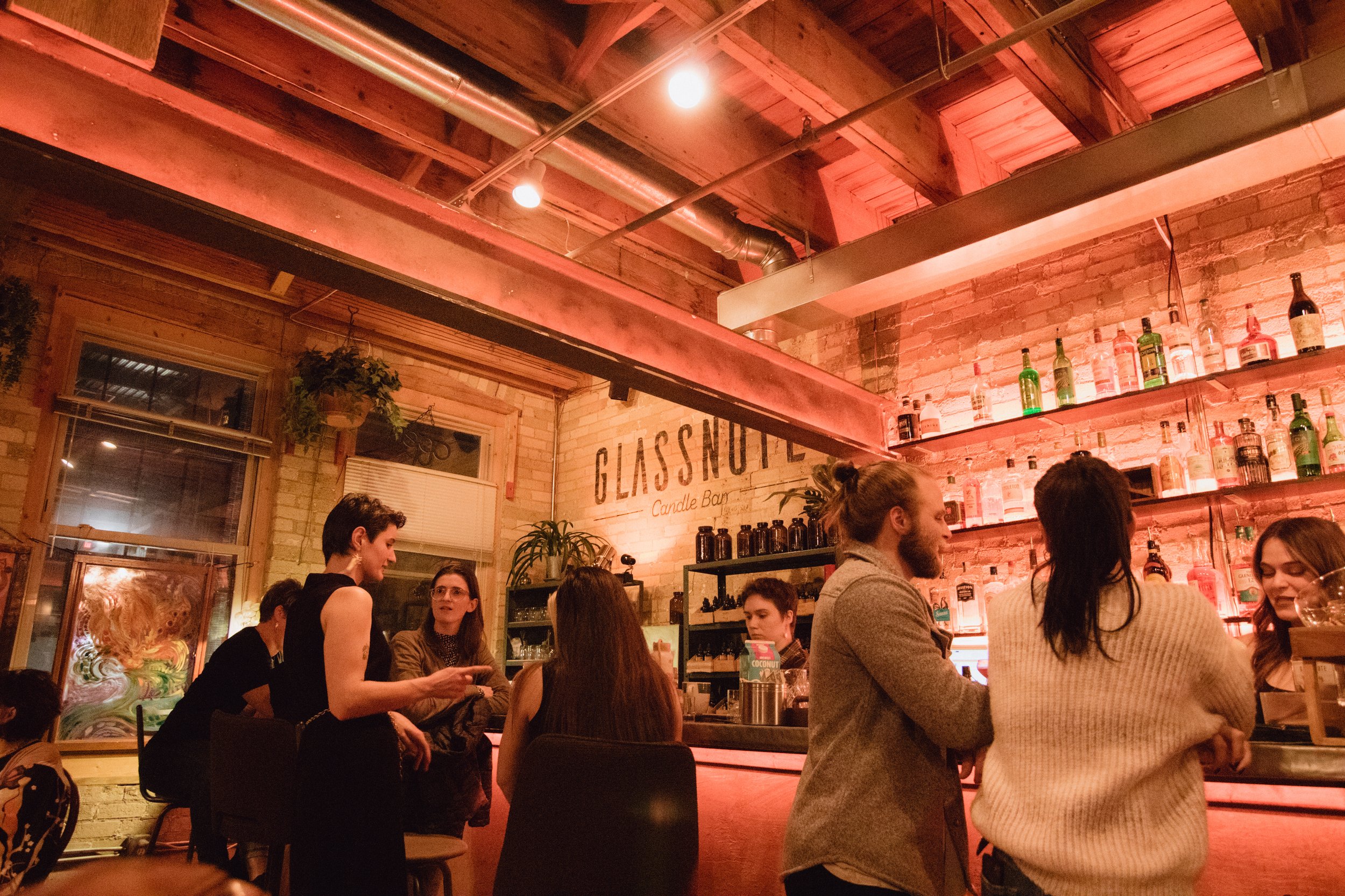  Artist and guests mingle at the bar in an old cream city warehouse at Hygge: A Pop Up Gallery curated by Milwaukee artist, Lauren Marie Nitka, at  Glassnote Candle Bar  in Walker’s Point, WI. 