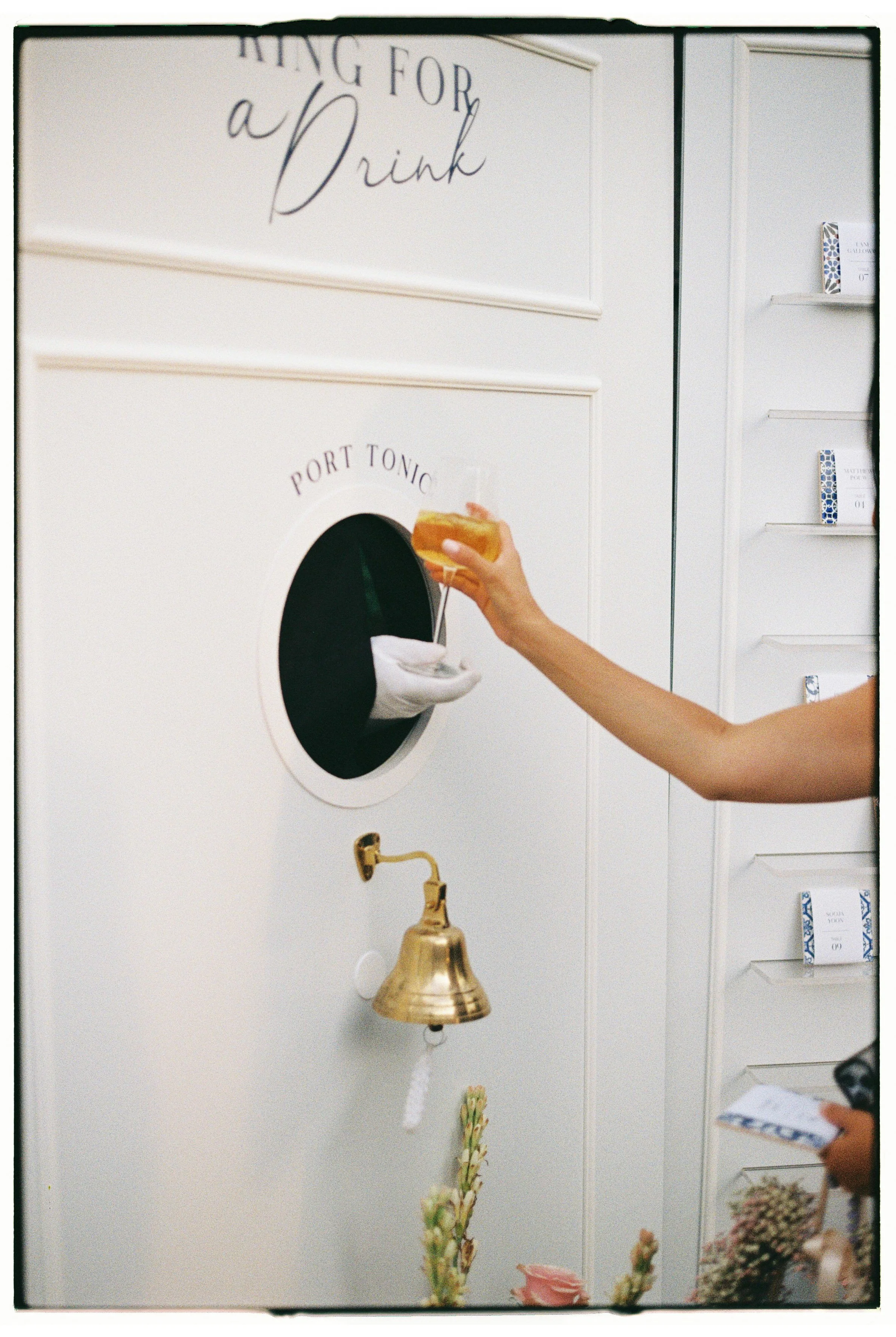 Person's hand dropping an orange drink into a to-go cup at a drink vending machine.