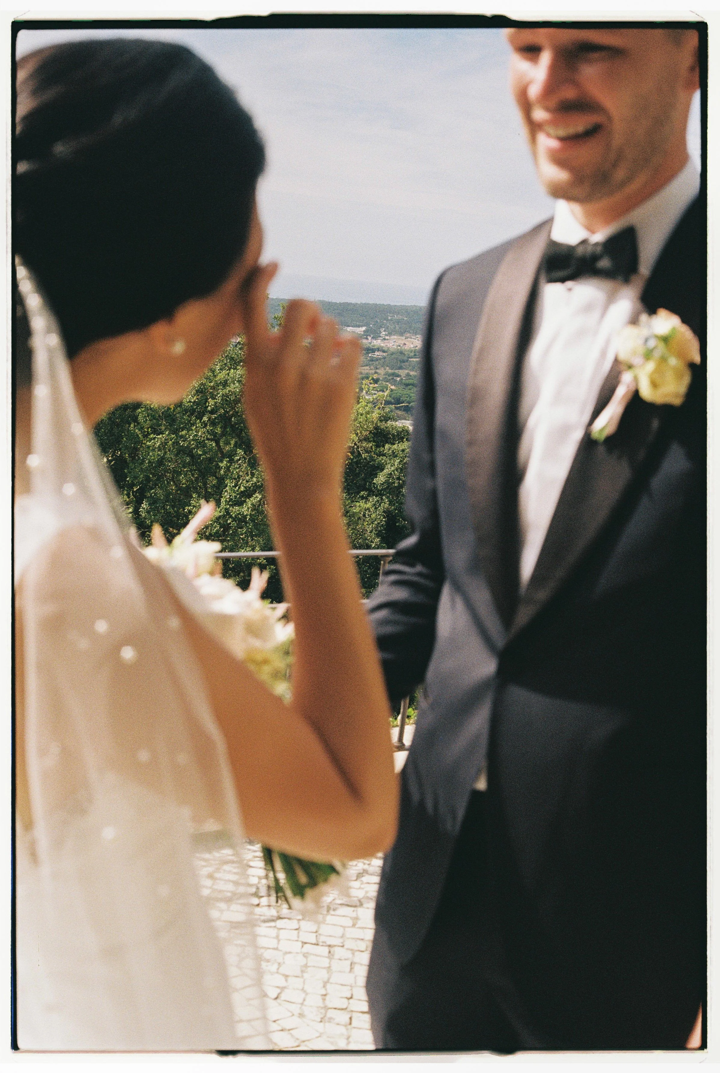 A wedding ceremony with a bride and groom outdoors, with trees and a scenic landscape in the background.