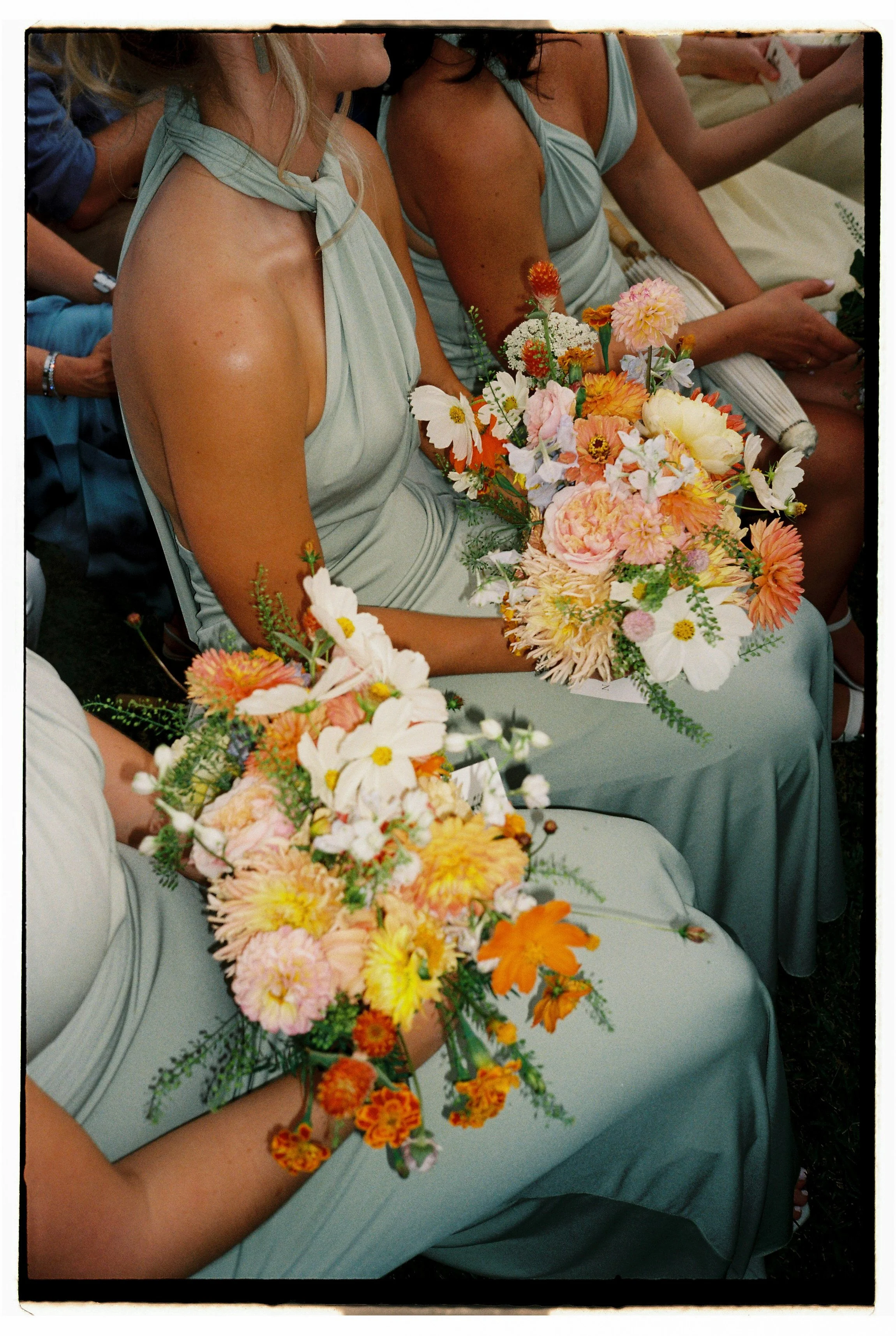 Women in light blue dresses holding colorful flower bouquets at a wedding or formal event.