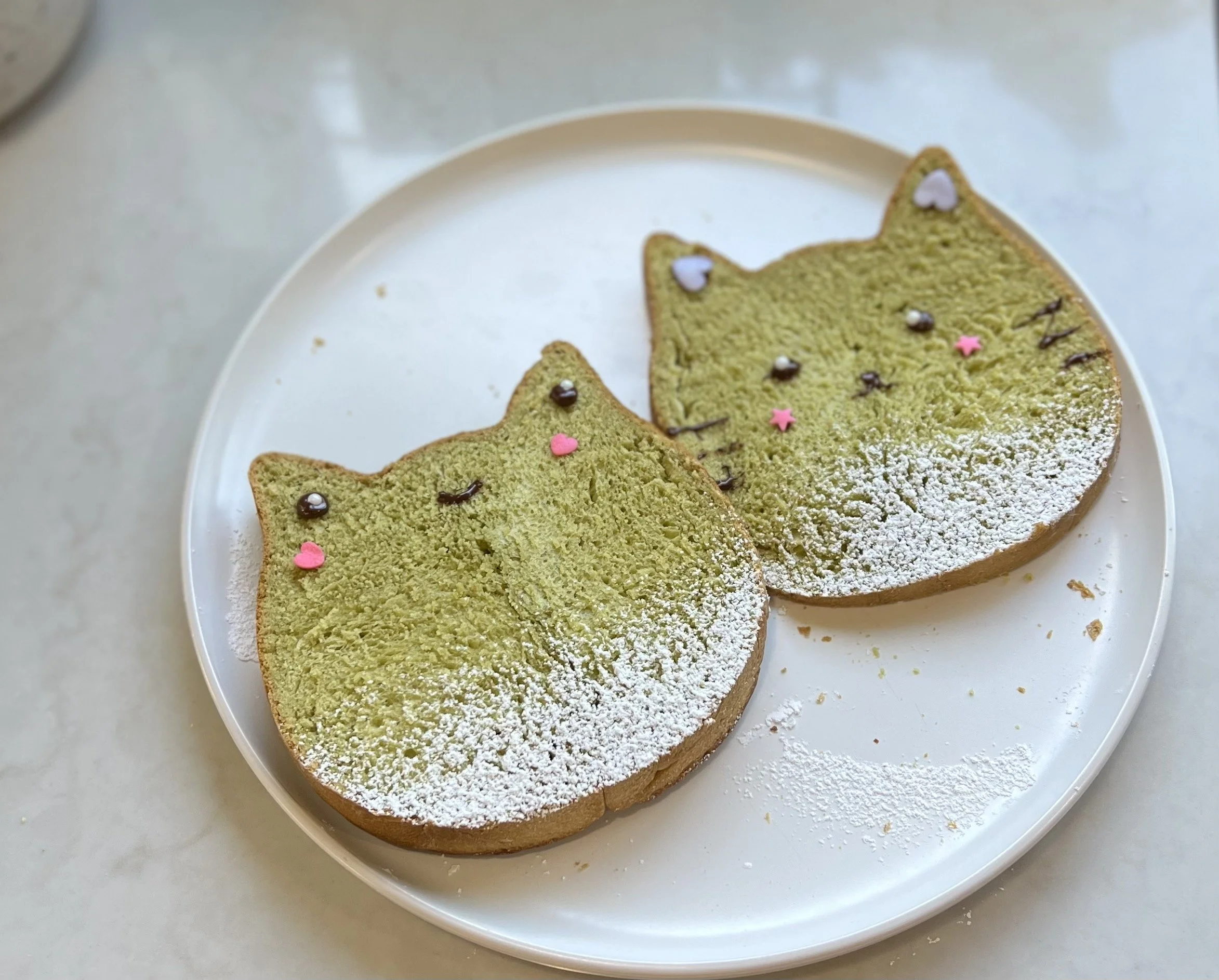 matcha milk bread with cat and frog shaped slices on white plate