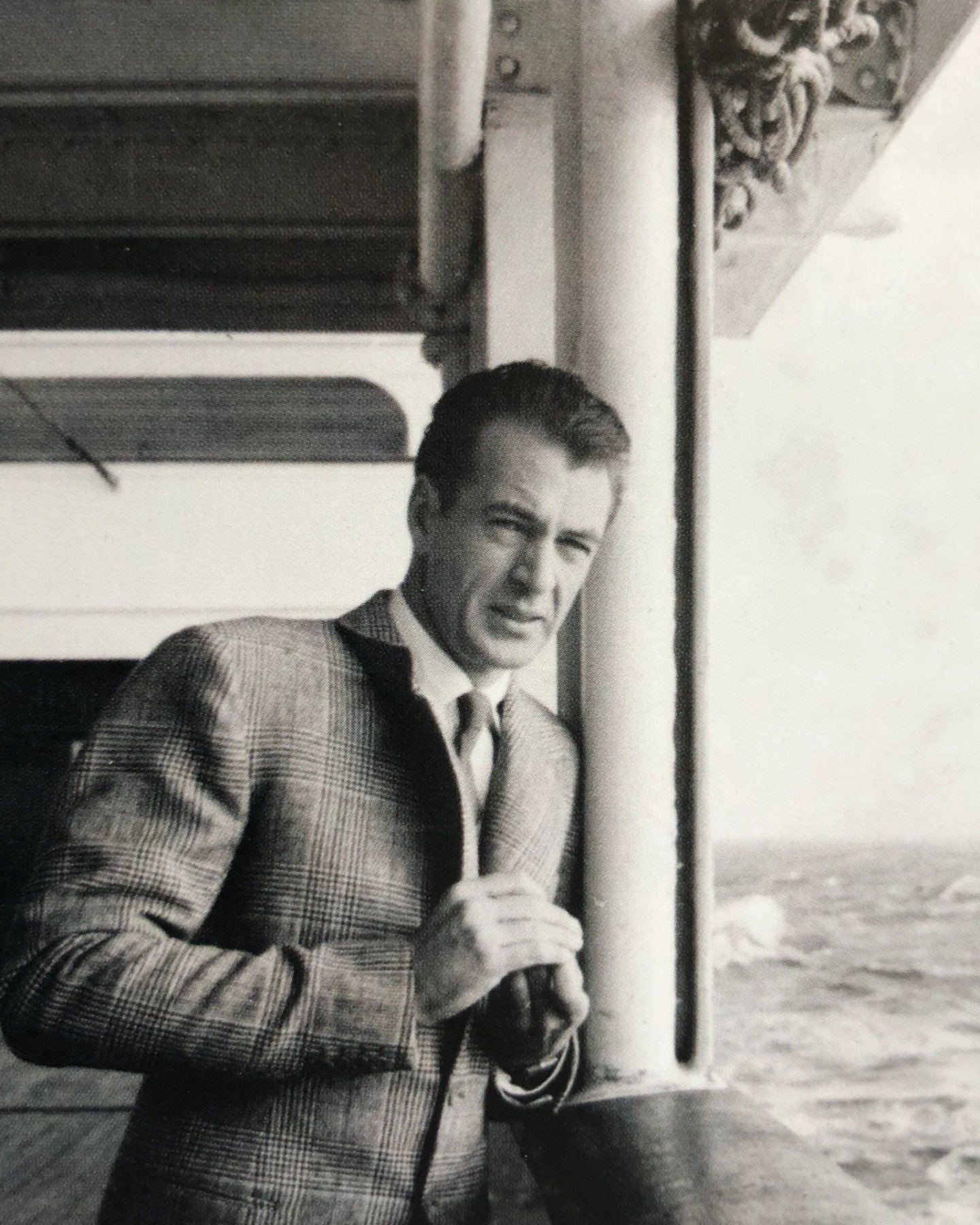 🎥🎩In today's spotlight, we're enchanted by the dashing allure of young Gary Cooper, captured aboard a ship in a moment of timeless sophistication.

Draped in a finely tailored suit, Cooper exudes an air of effortless elegance, his gaze as captivati