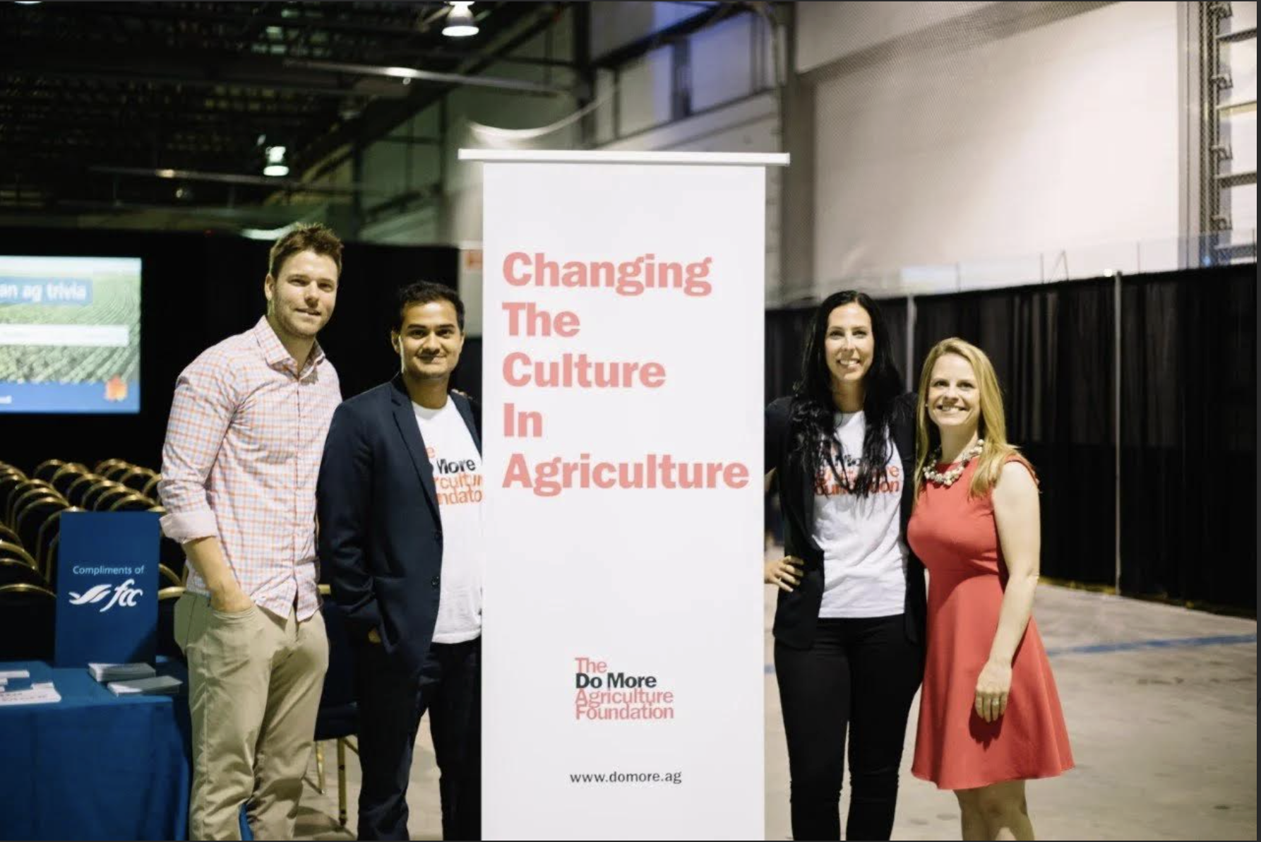 Four adults posing next to a banner reading Changing The Culture in Agriculture.