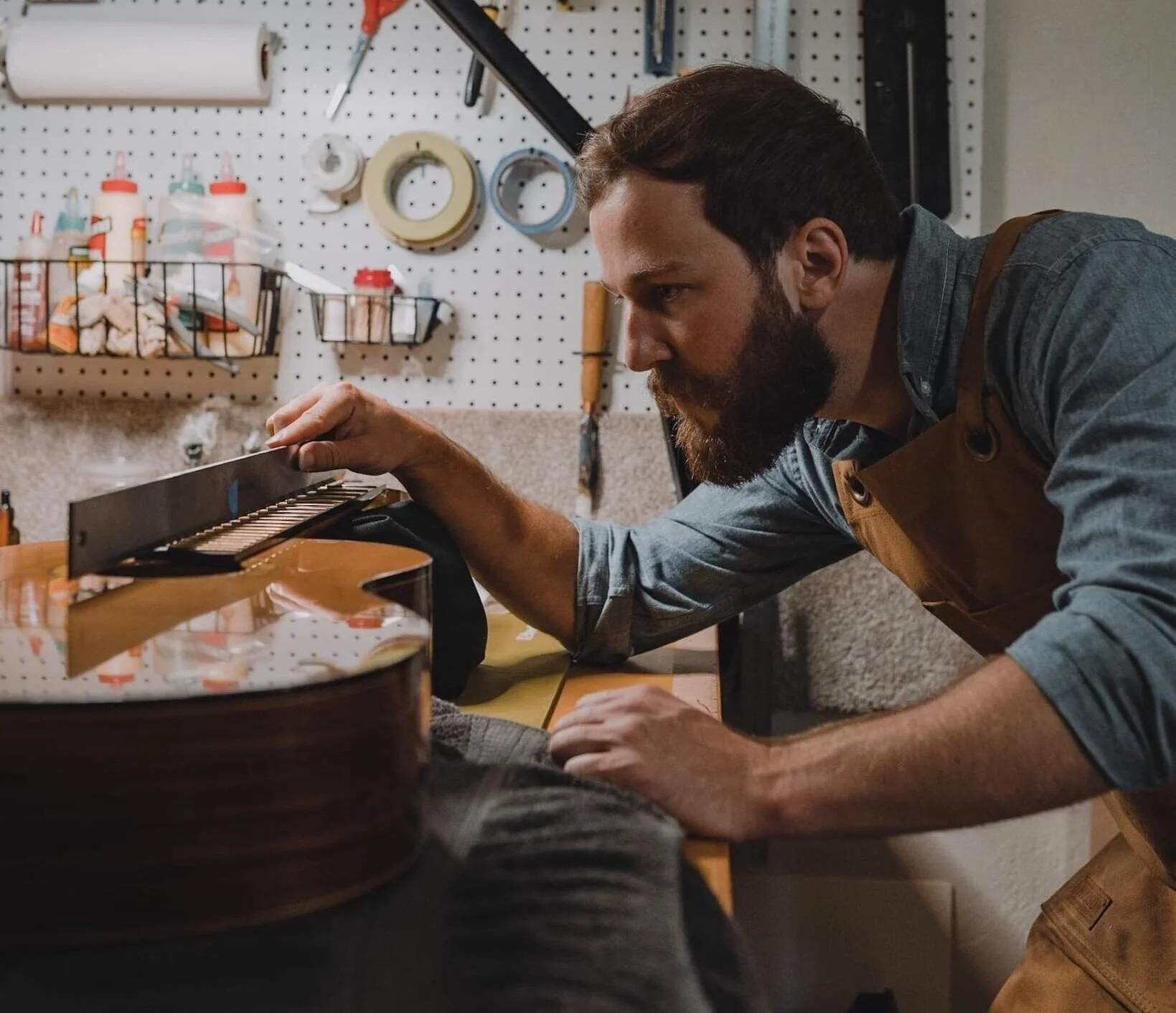 Luthier Andrew Lesley Smith in his workshop examining a guitar.