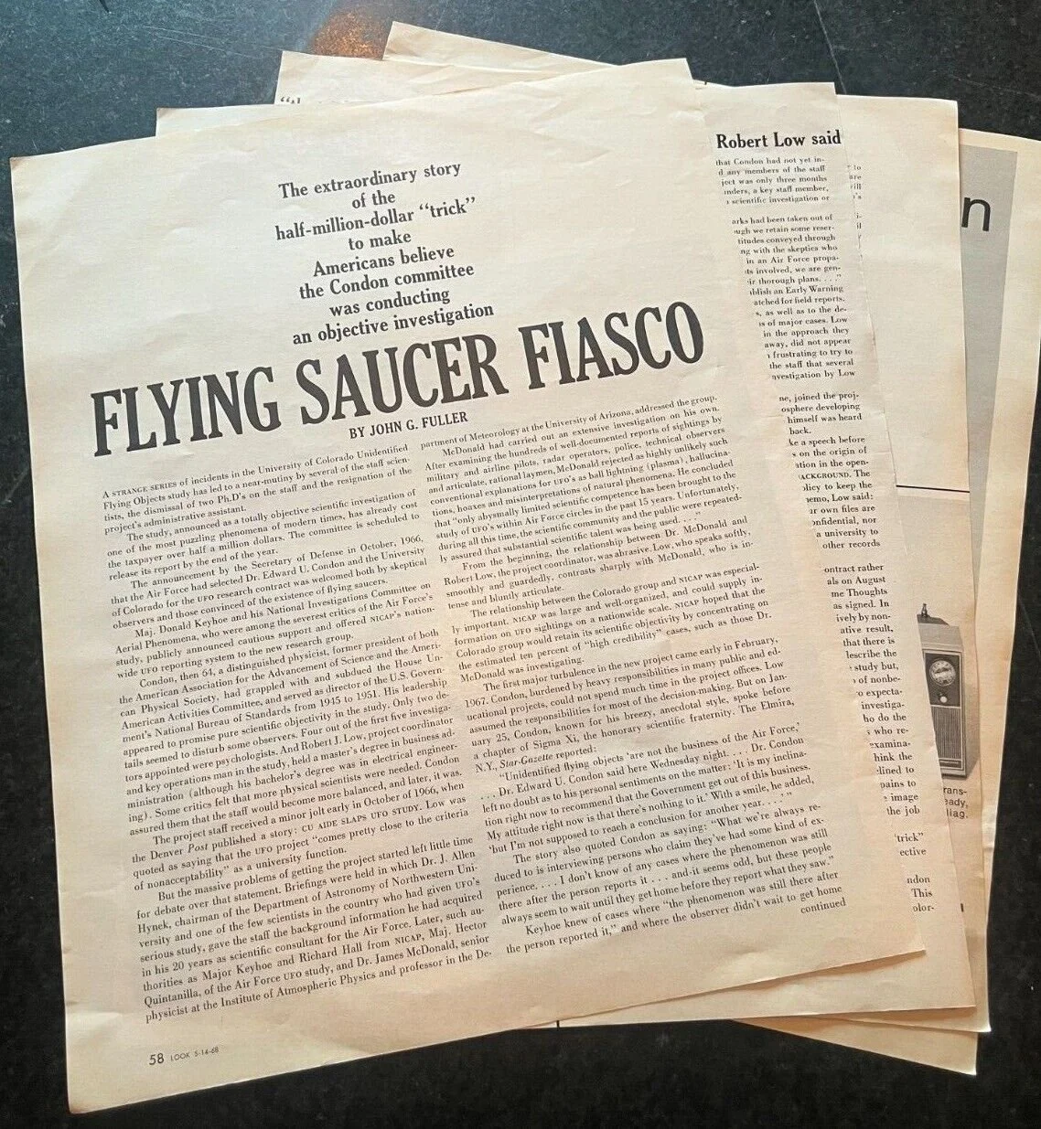 A stack of newspapers, with the top one titled "Flying Saucer Fiasco" and featuring an article about a supposed UFO incident.