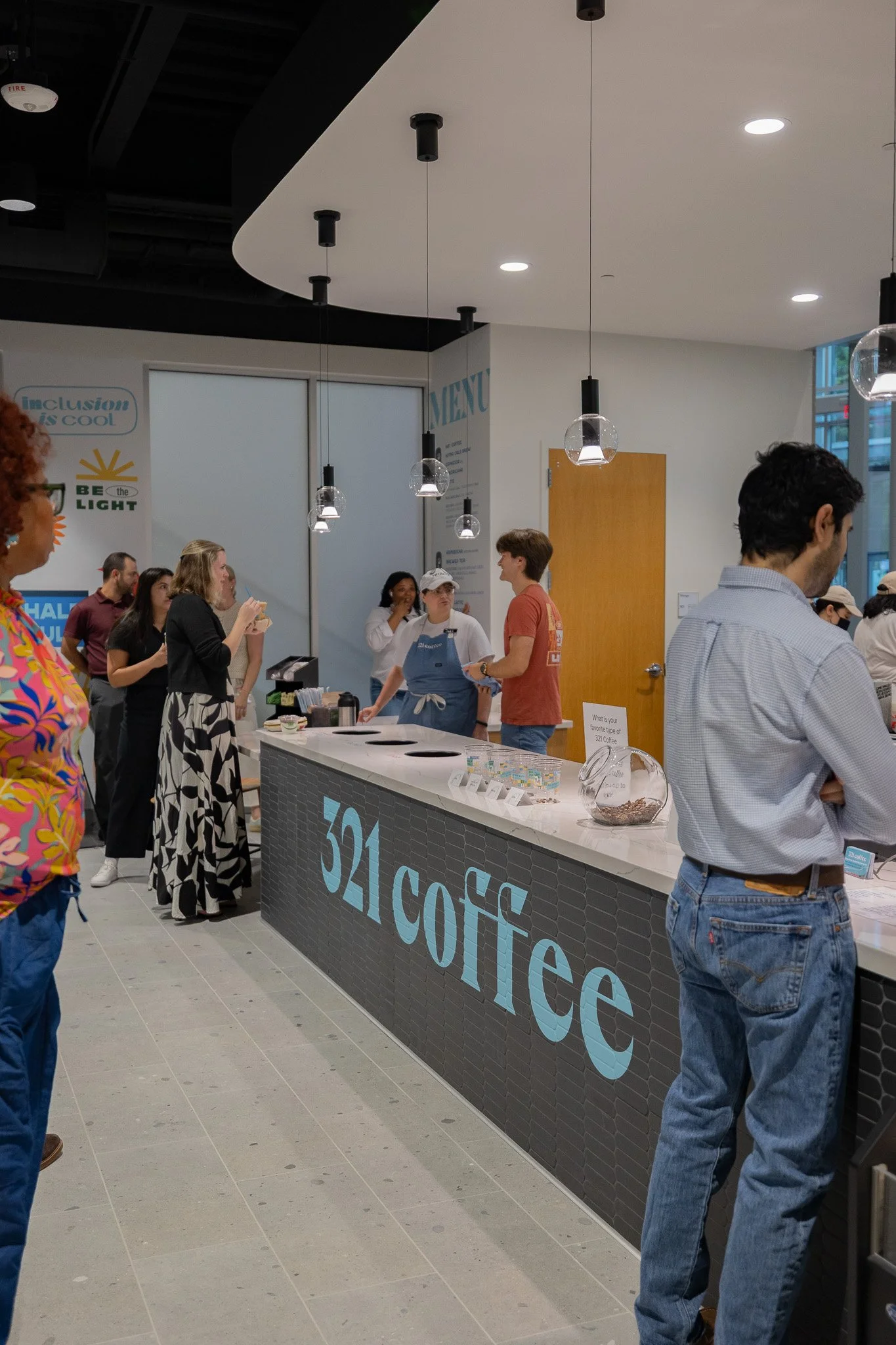 The new cafe features modern sleek features, including a long counter in the front with a large, teal 321 Coffee logo..