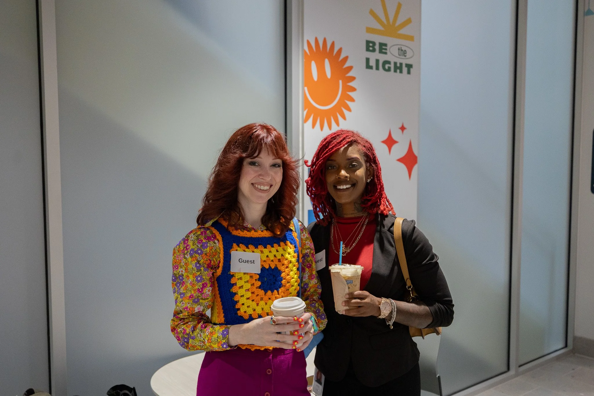 Two woman smile for a photo while enjoying coffee in the new space.