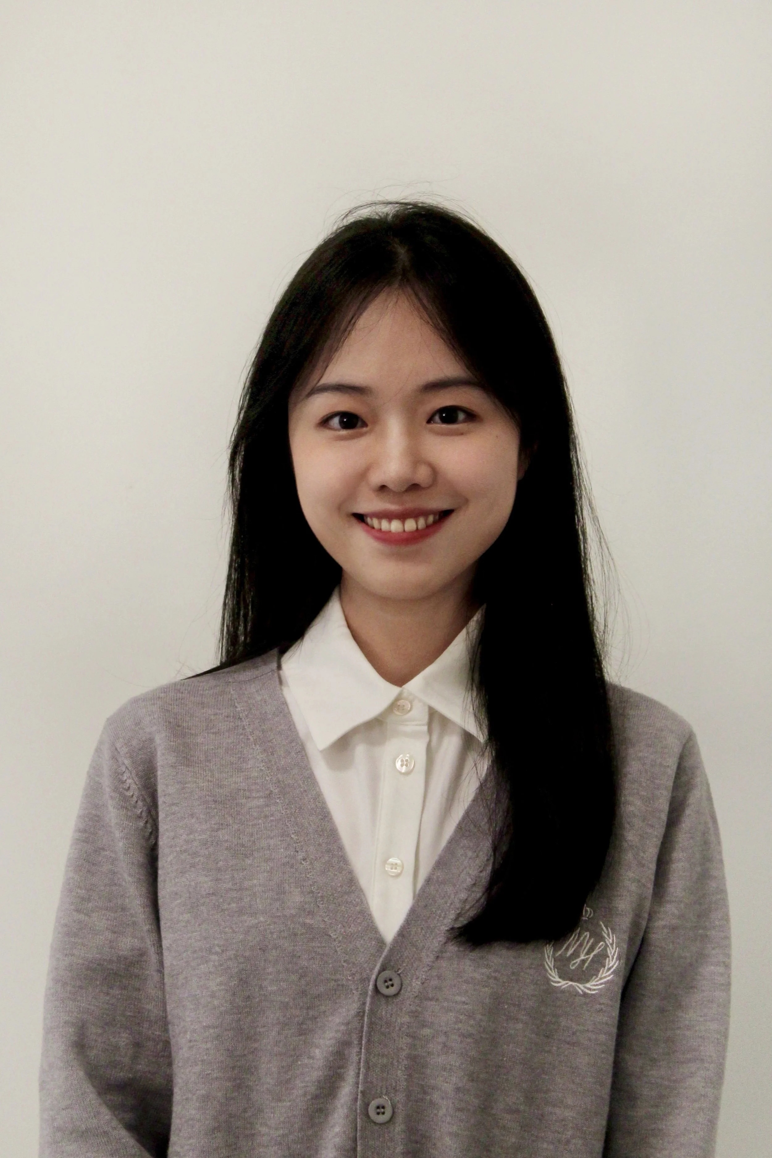 Xiaoyan (Casey) Wang- a woman of Asian desent. She has long dark straight hair. she is smiling and is waeing a grey sweater with a white button up shirt.