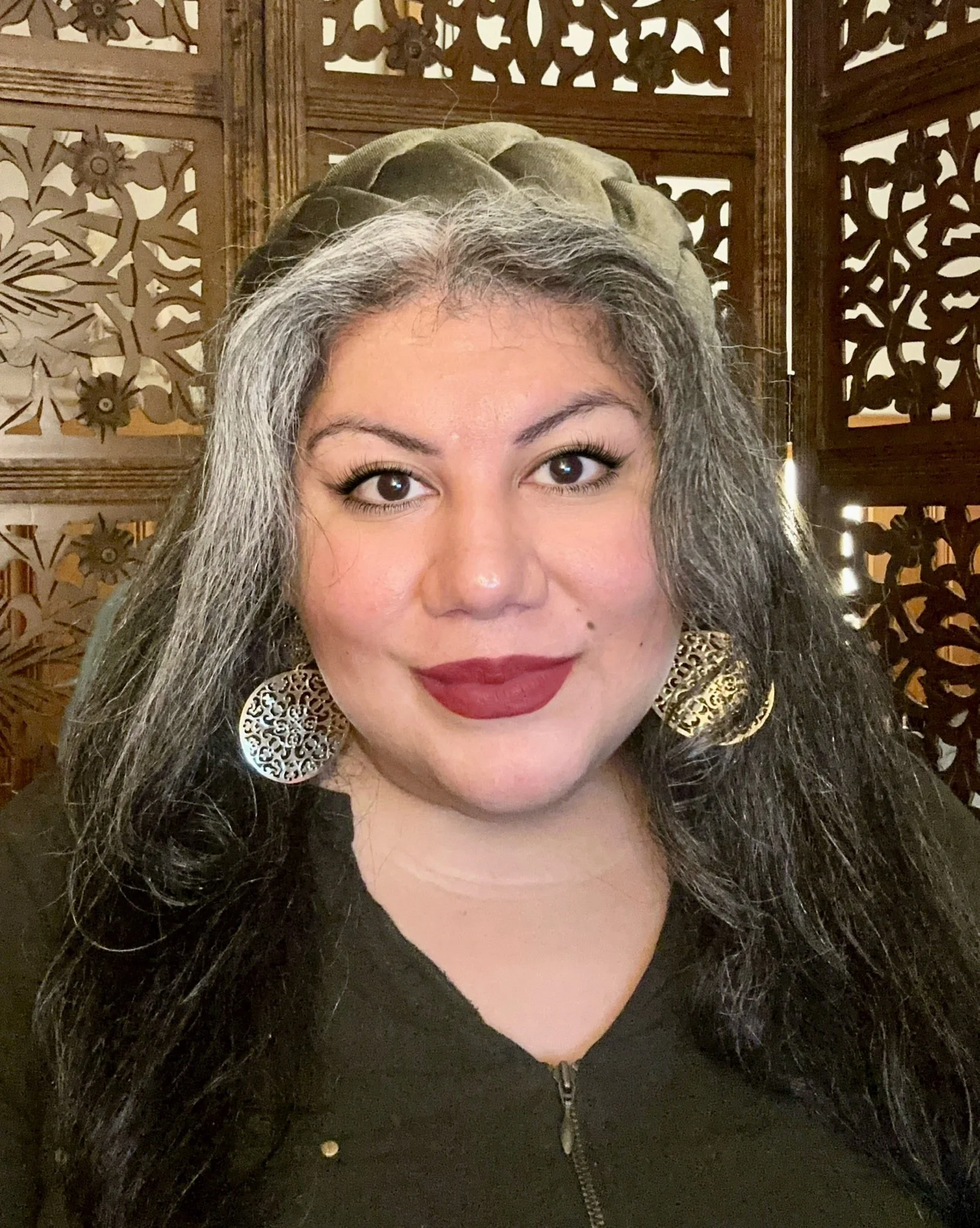 Smiling woman with long dark black and grey hair.