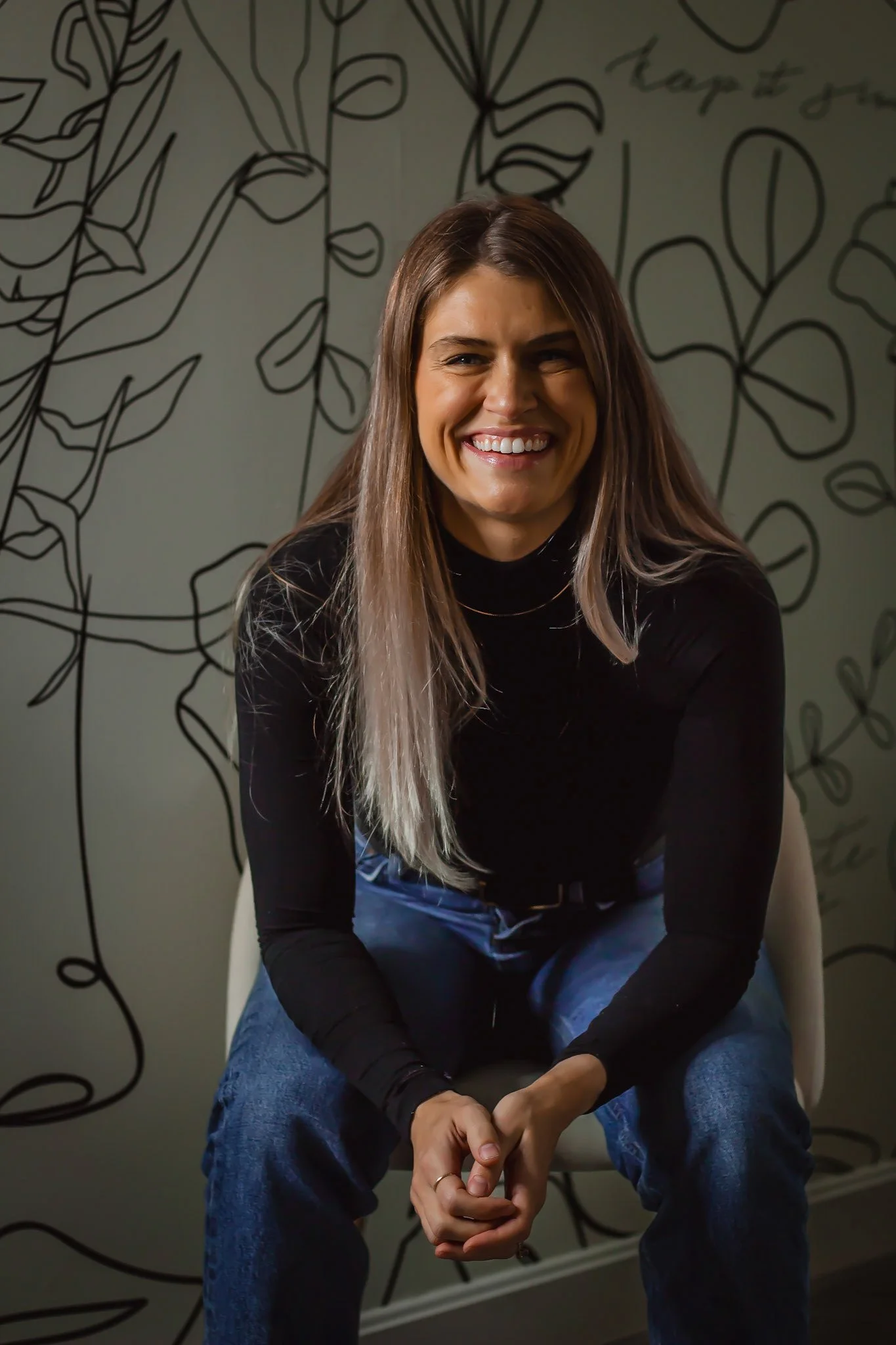 Tabatha Walker, Founder of Lash Browtique, sits in a black chair and smiles.