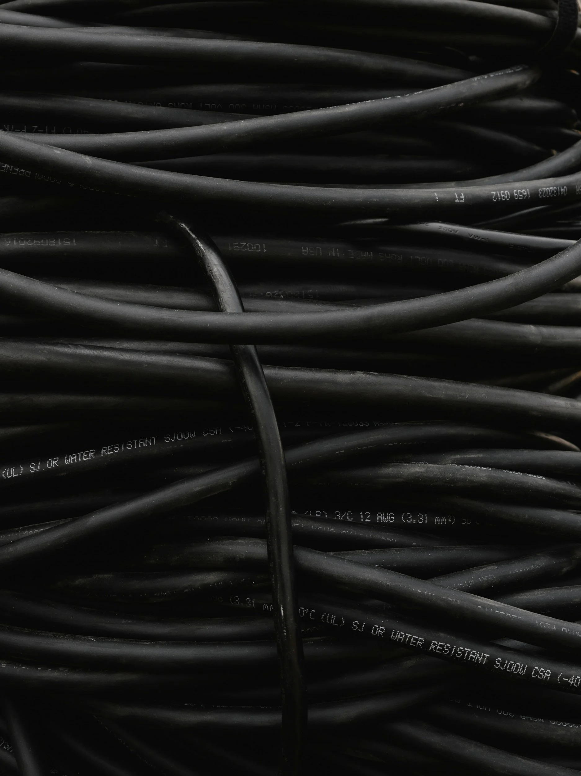 Close-up of tangled black electrical wires with white printed text indicating specifications.