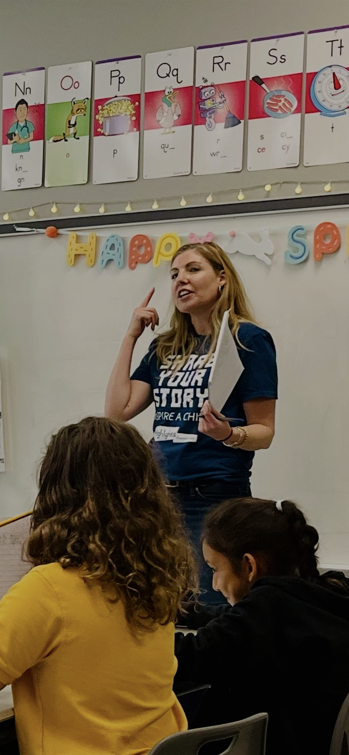 Author E. E. Dowd pointing to her head and encouraging students. in a classroom to think.