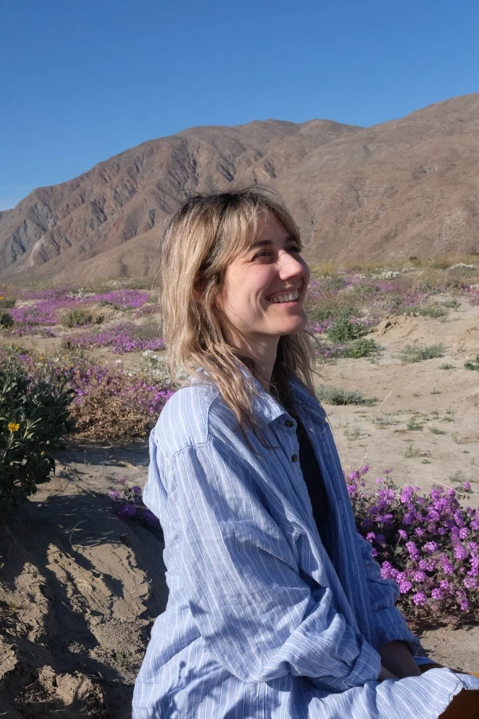 somatic therapist sitting in nature, smiling and regulated