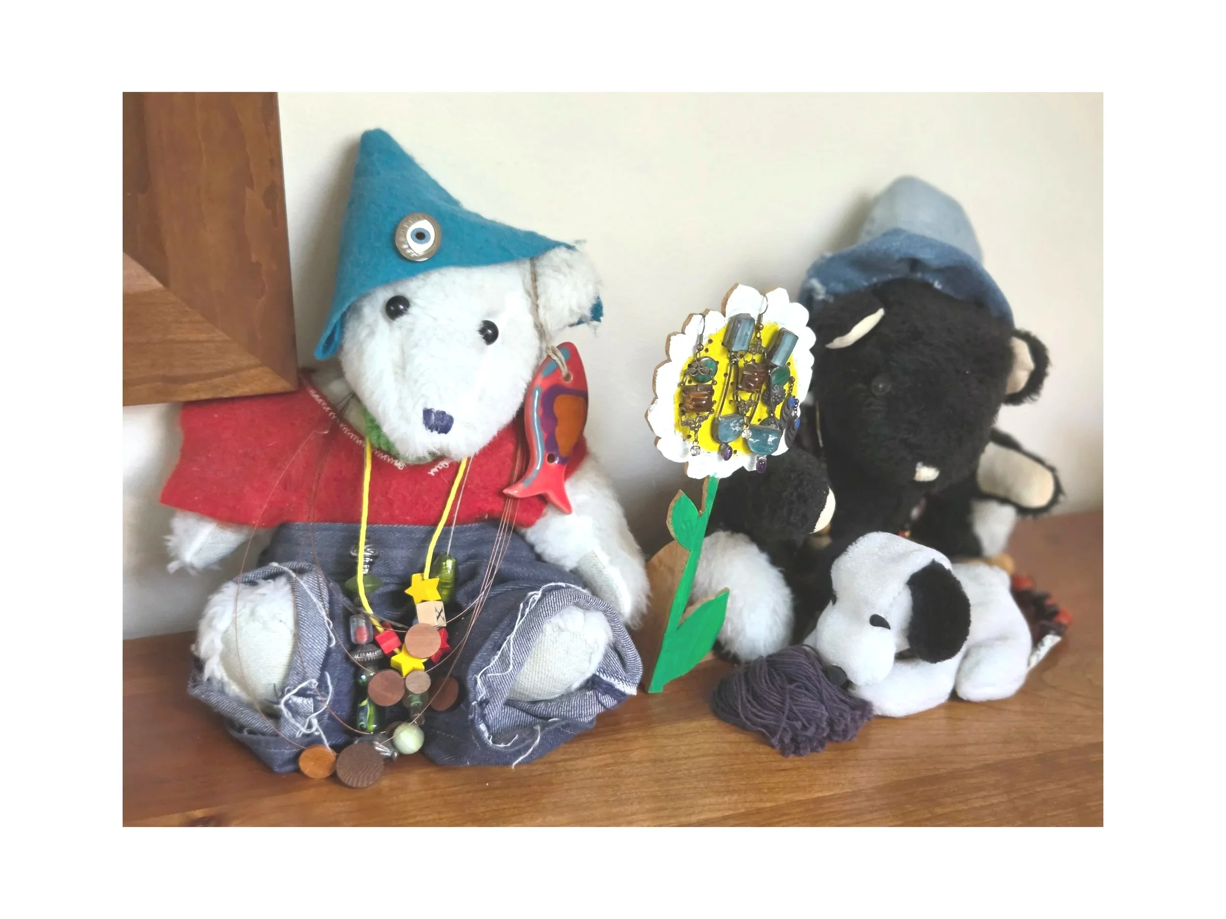 Jill made these two bears, all their clothes and jewelry, except for the pin on the white bear's hat made by her daughter Cassie. Jill also created the wooden flower standing between the bears.