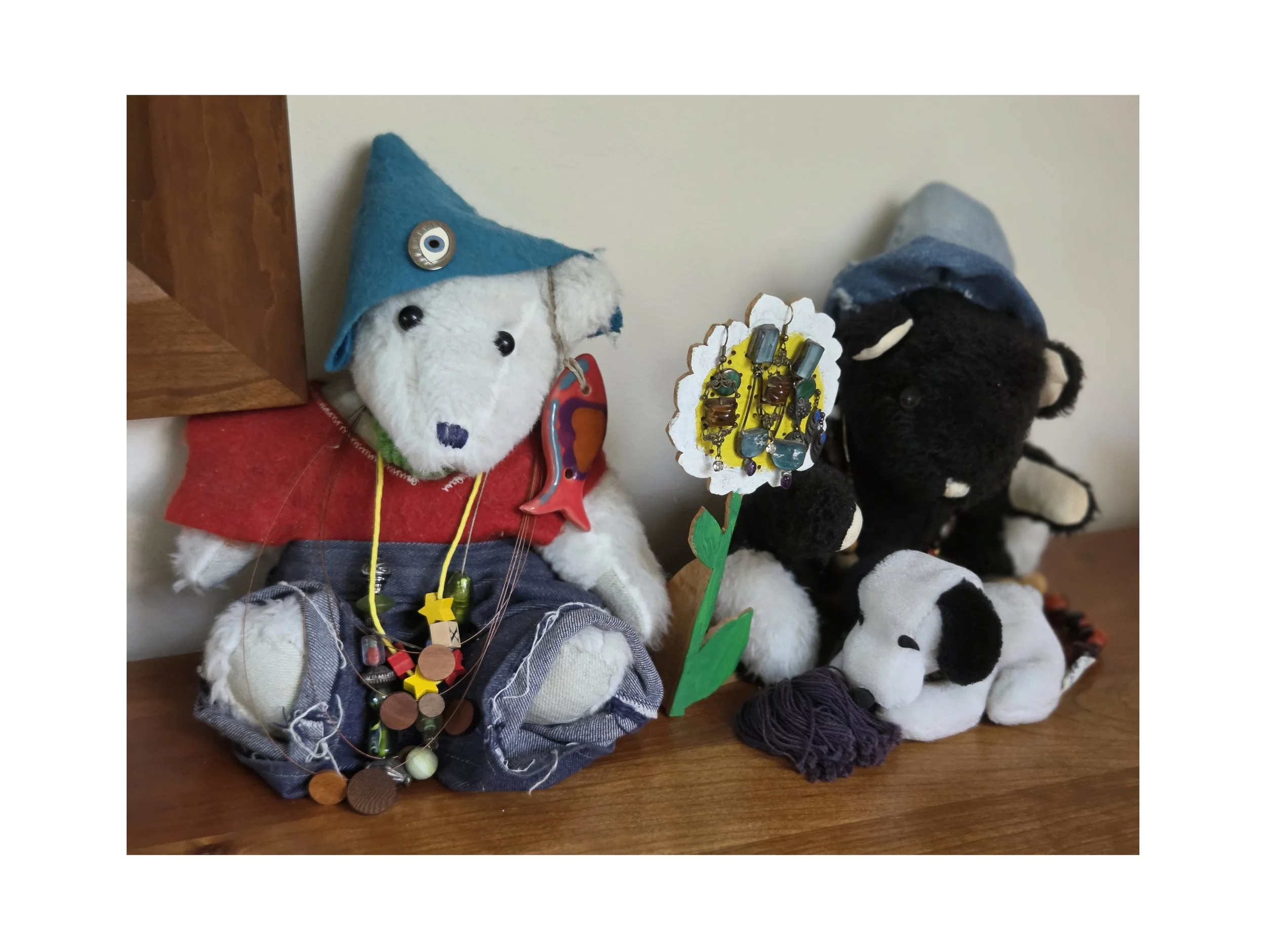 Jill made these two bears, all of their clothing and some of their jewelry. Jill's daughter Cassie made the pin on the white bear's hat. Jill also created the wooden flower standing between the bears.