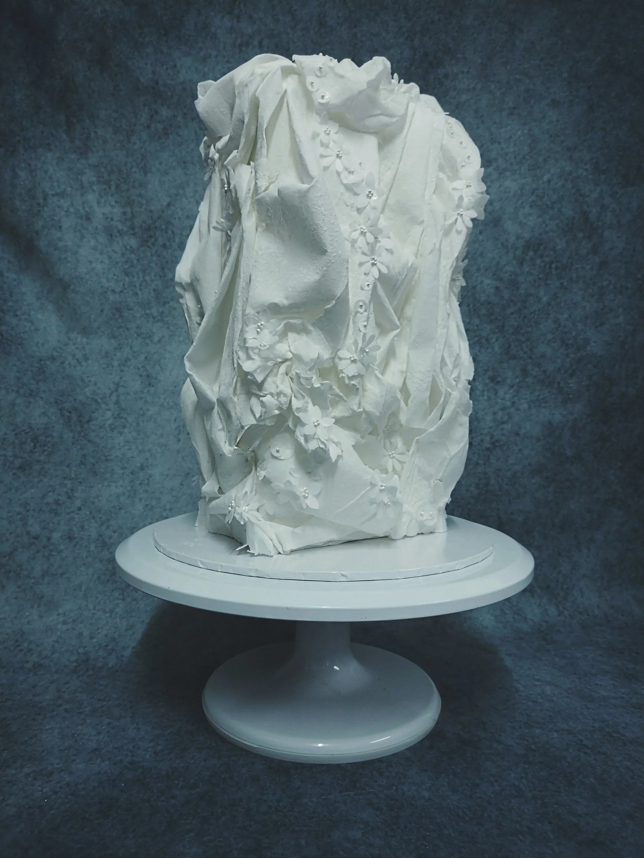 Not just a white wedding cake… a white wedding statement! Designed to echo the bride’s gown, delicate wafer paper is softly draped like fabric in motion, finished with tiny handcrafted white florals and subtle pearl details. Contemporary yet abstract