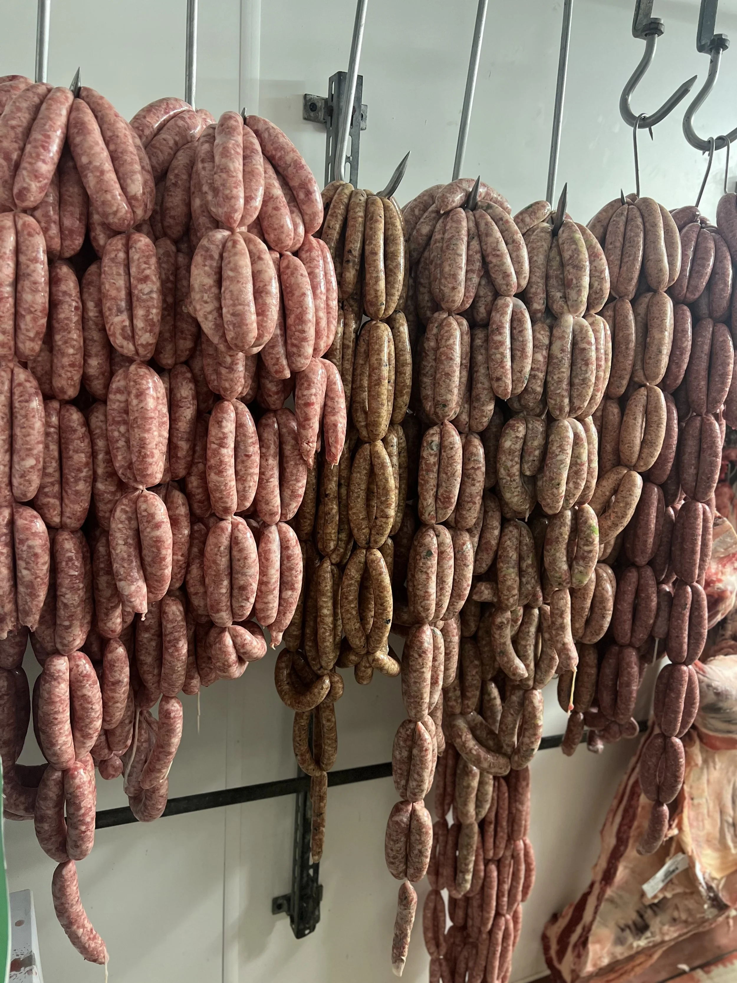 An assortment of raw sausages hanging on hooks in a meat shop.