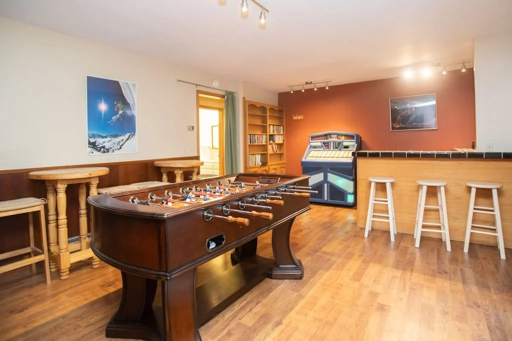 Game room of a mountain house in Lake Tahoe CA. In the game room there's a foosball table, jukebox and bar with stools