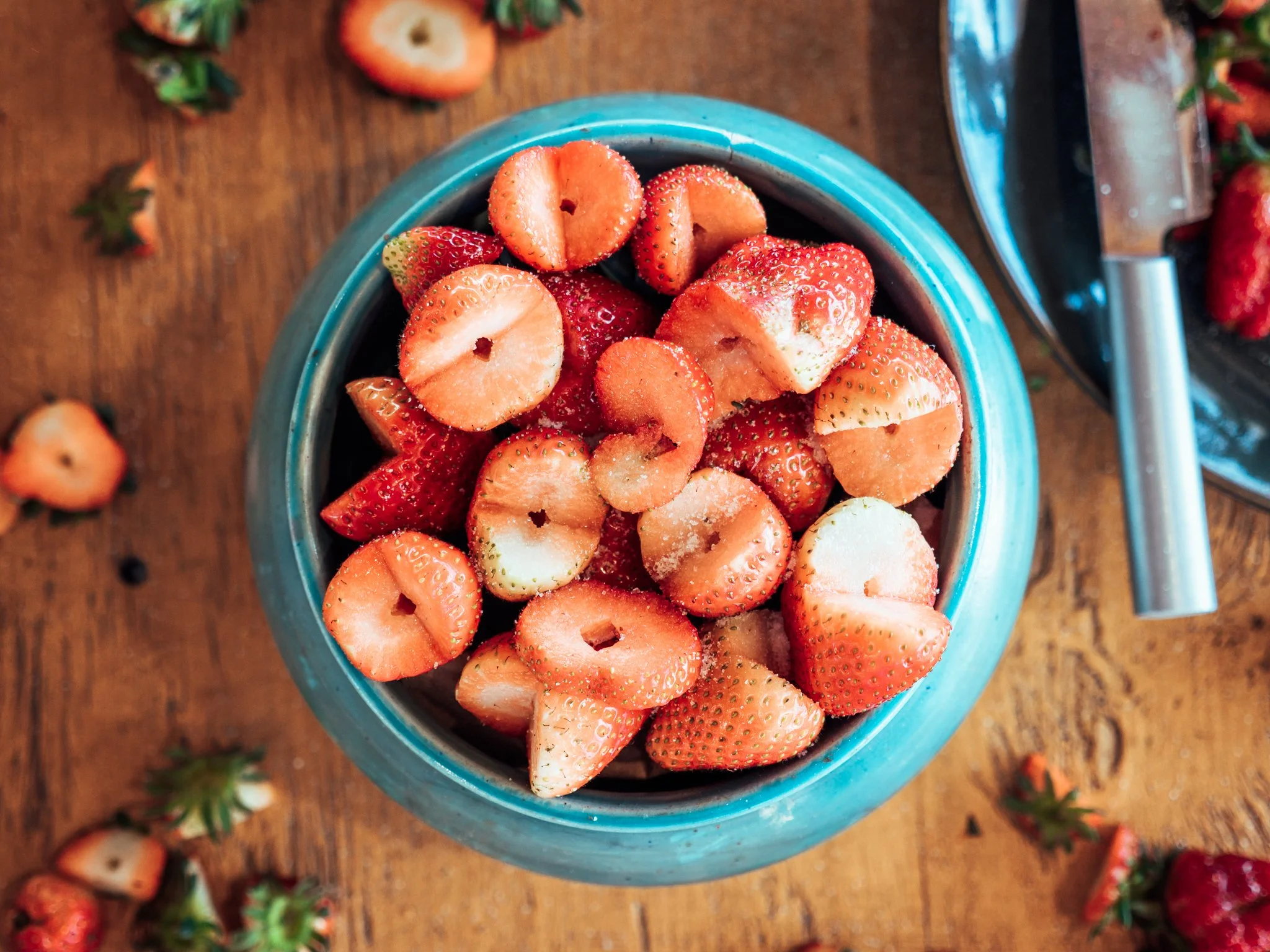 Fresh strawberries in a bowl sprinkled with sugar, placed on a rustic table – vibrant food photography showcasing natural sweetness.