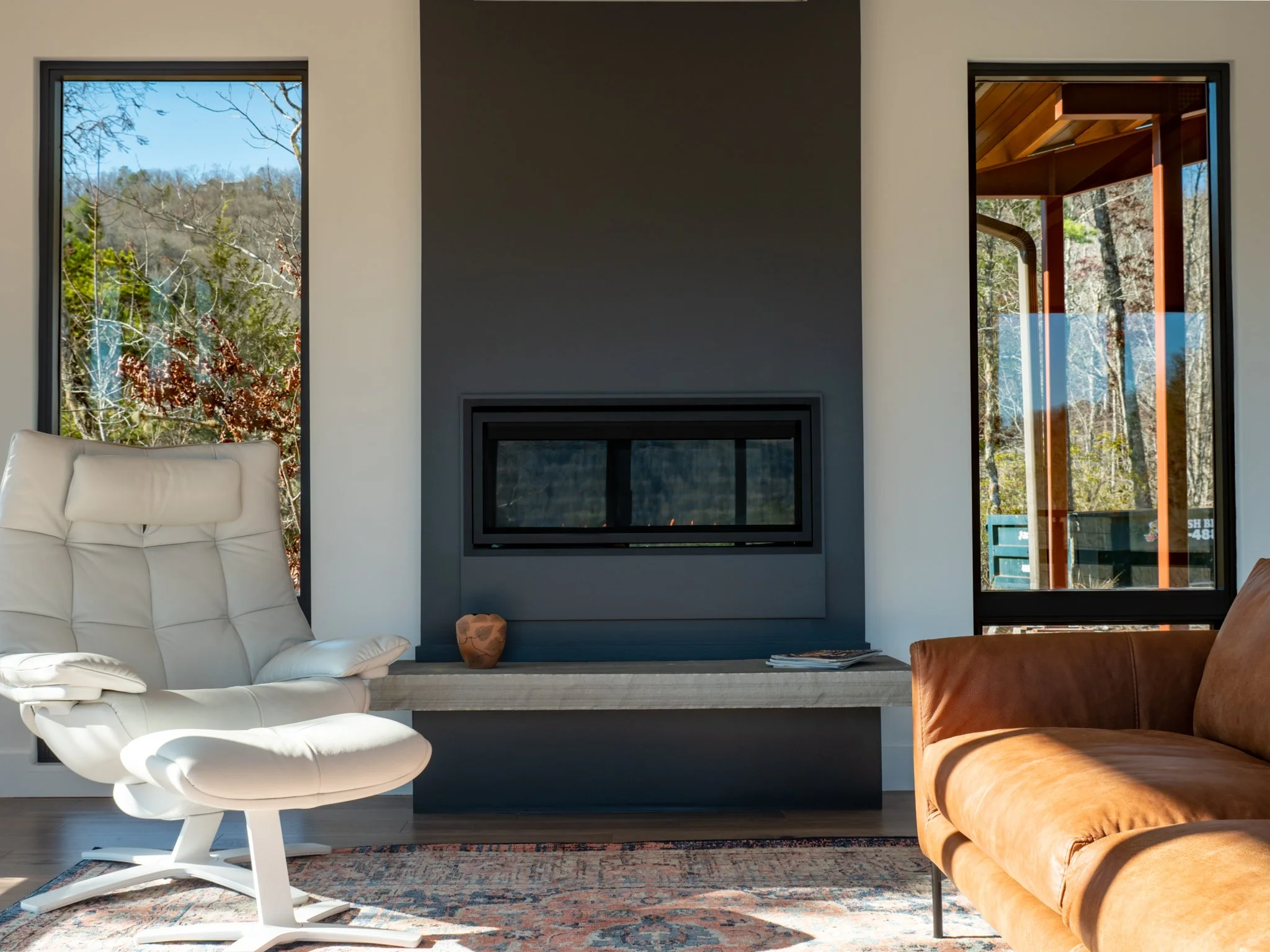 Stylish modern living room featuring a sleek concrete fireplace and large windows that let in natural light, creating a bright and airy atmosphere.