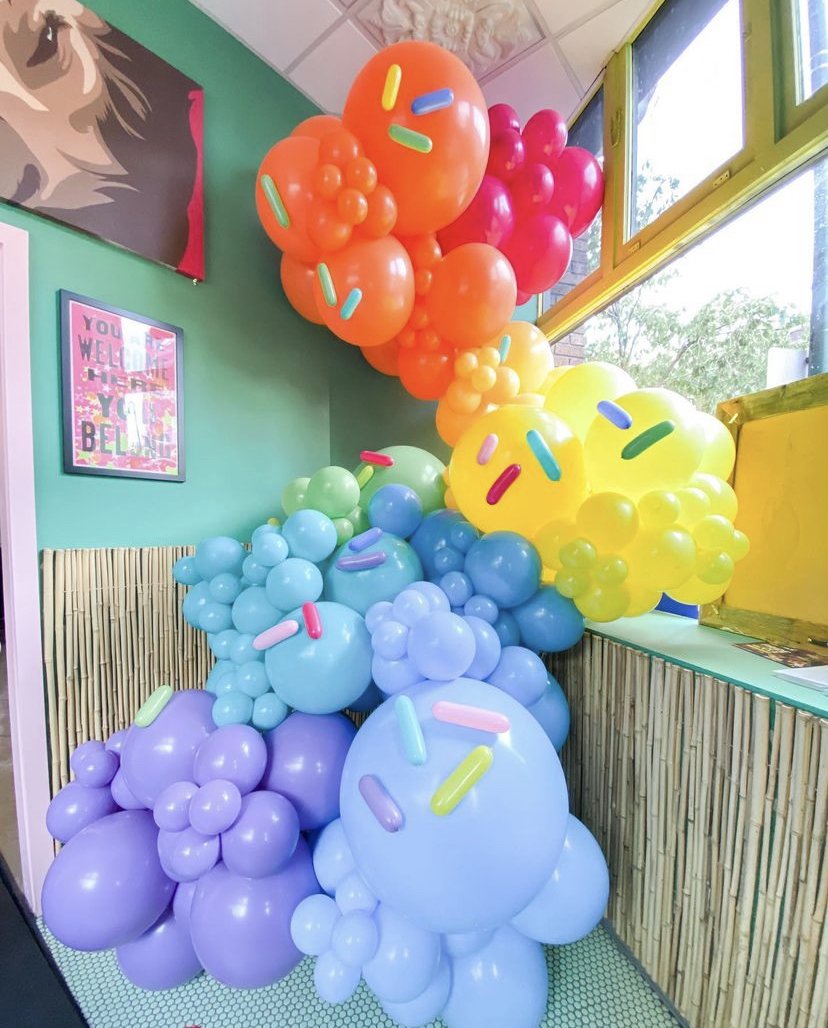 A rainbow colored balloon garland with rainbow balloon sprinkles
