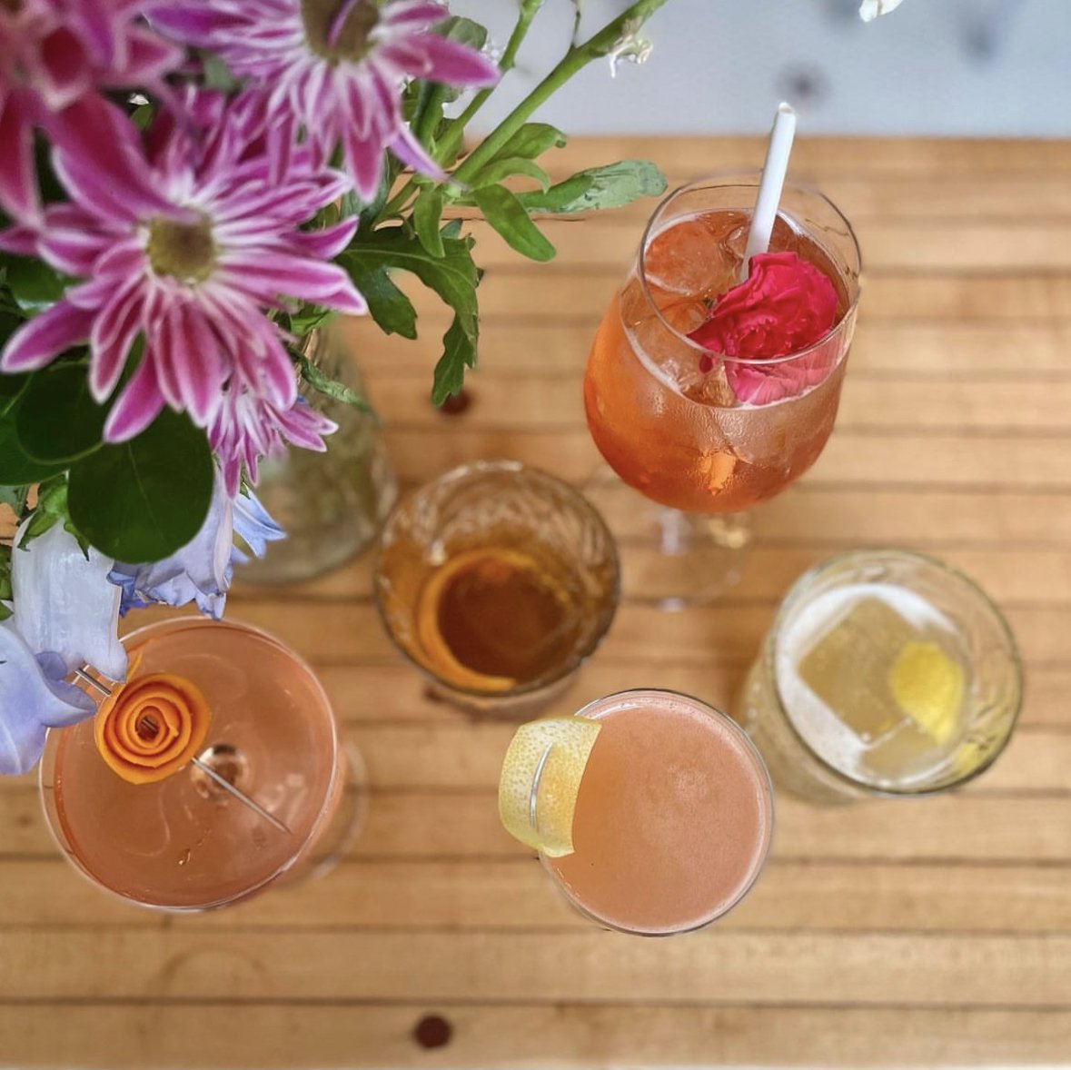 An overhead shot of bright colored cocktails on a wooden table at Lorelei in Pittsburgh.
