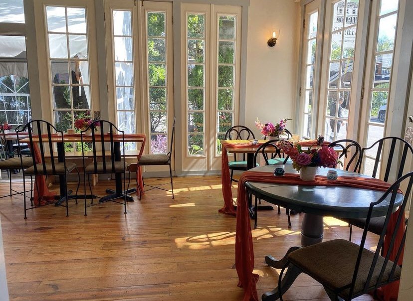 Seating area in Point Breezeway with wooden floors, french doors, and florals.