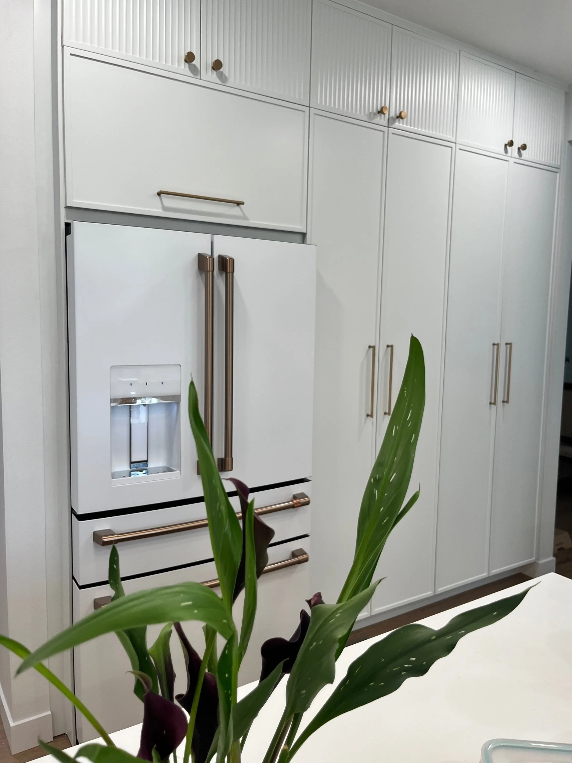 White kitchen with a white cafe refrigerator and brass hardware