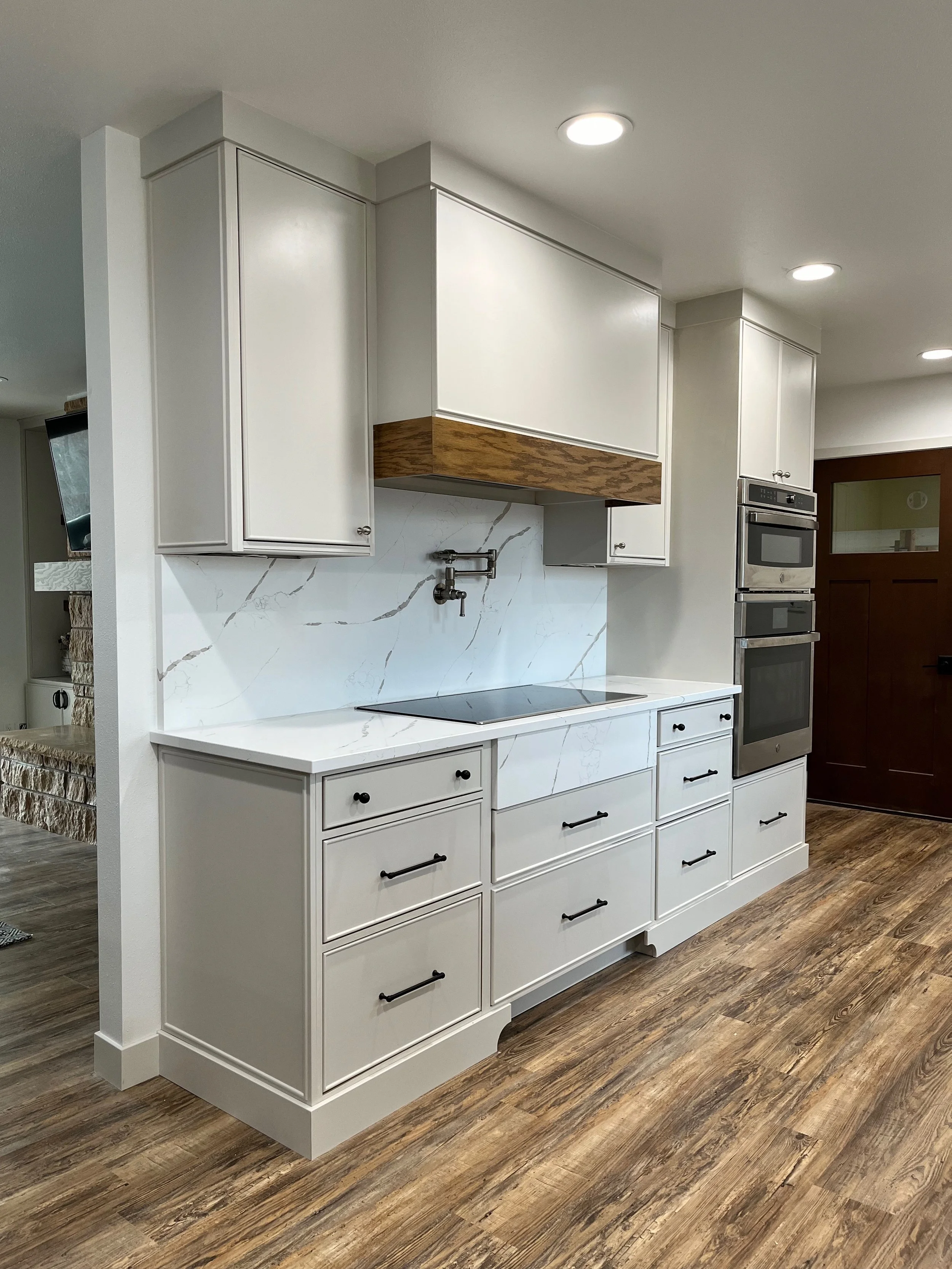Modern kitchen with white cabinets, marble backsplash, and built-in double oven.