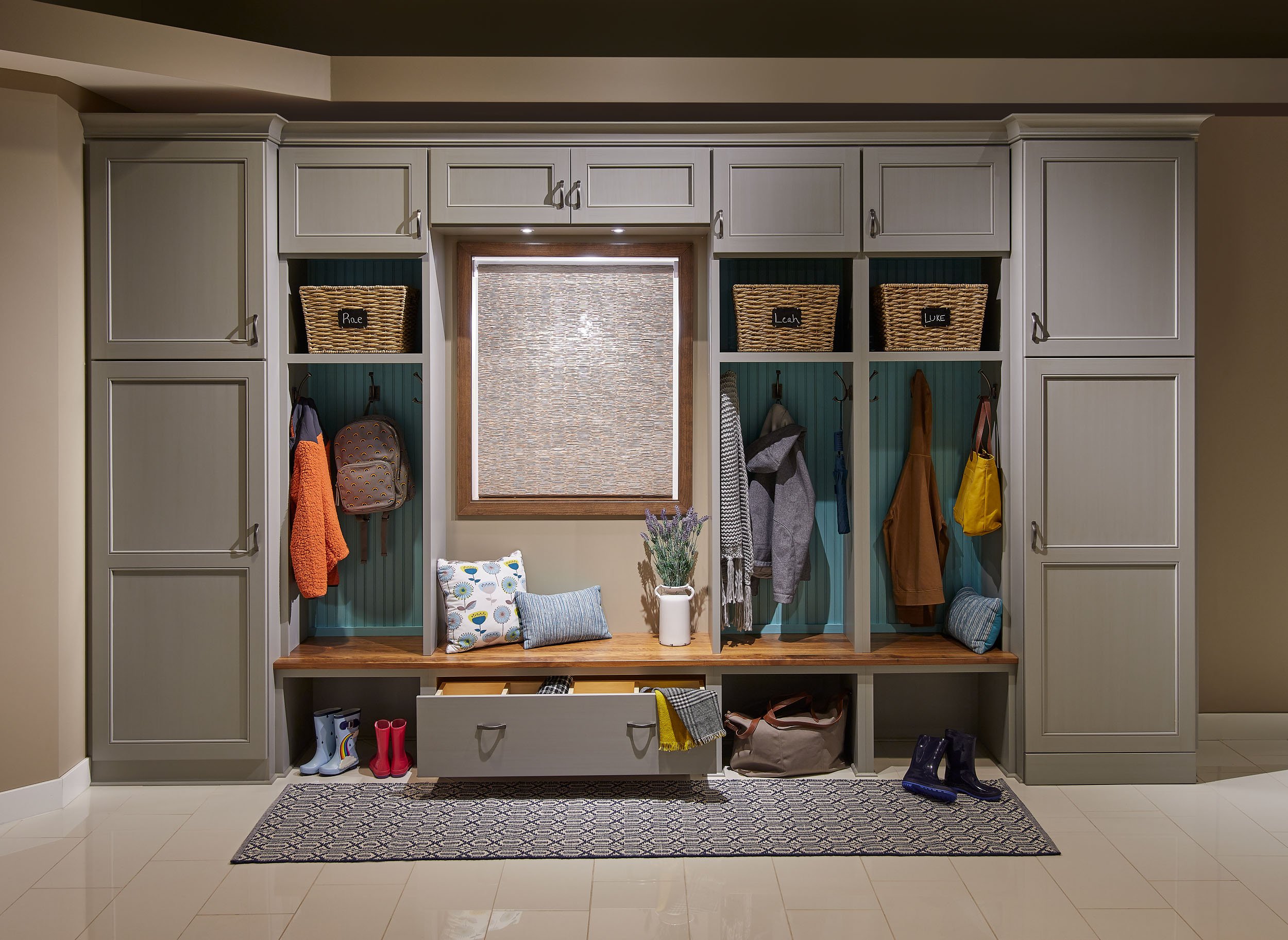 Mudroom with built-in storage, hooks with coats, boots, and shoes, and a window.