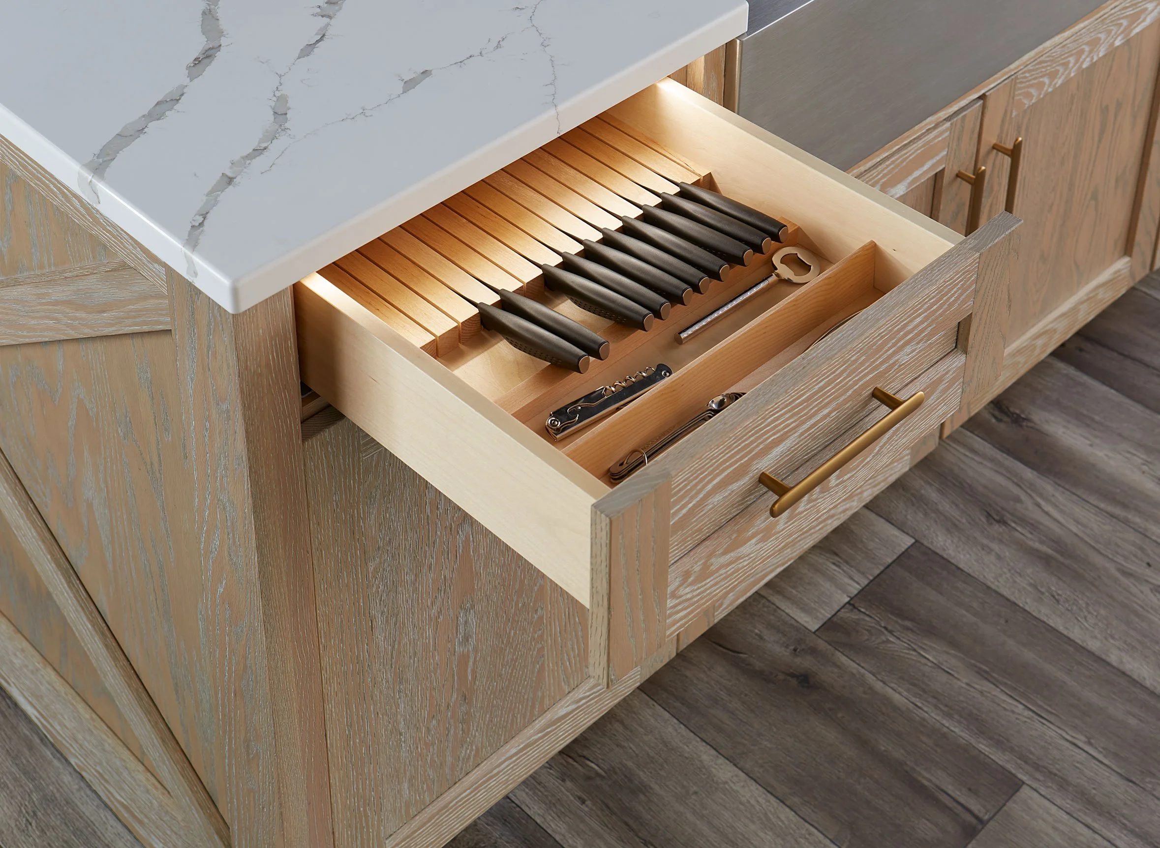 Kitchen drawer containing black kitchen knives, a corkscrew, a bottle opener, and a can opener.