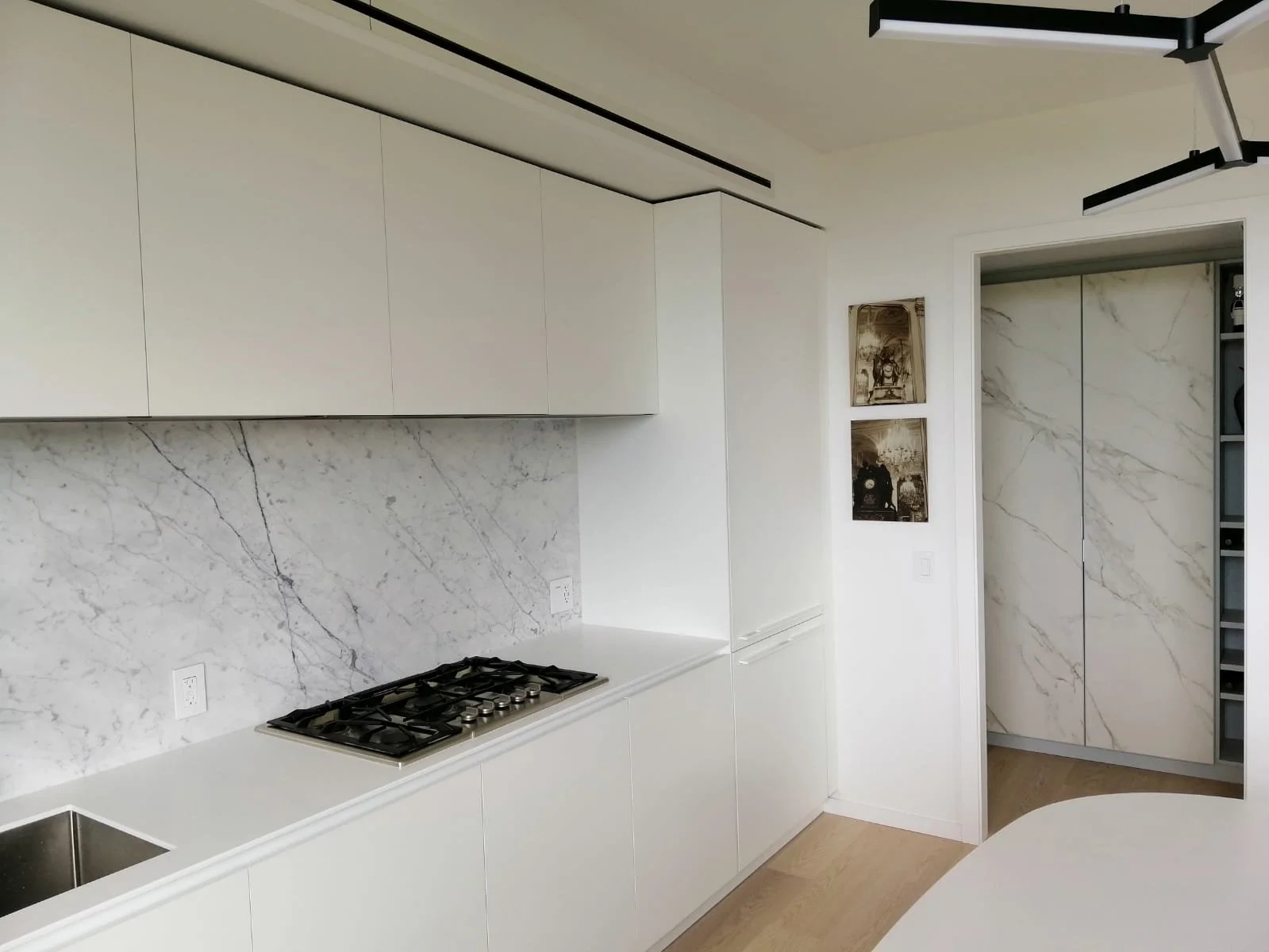 Modern kitchen with white cabinets, marble backsplash, and a built-in gas stove.