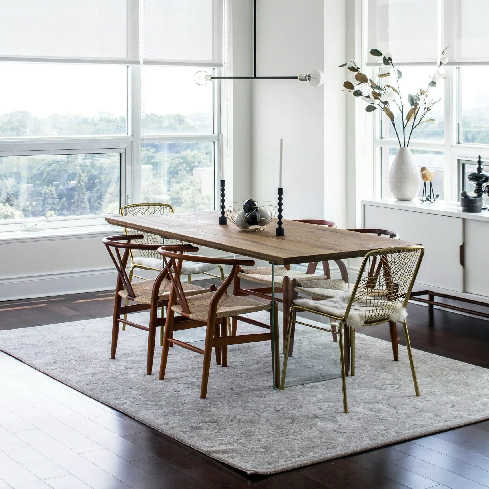 This modern dining room features white oak dining table with natural walnut wishbone chairs atop of chocolate brown walnut floor plank.