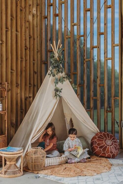 Two girls sitting inside a teepee reading